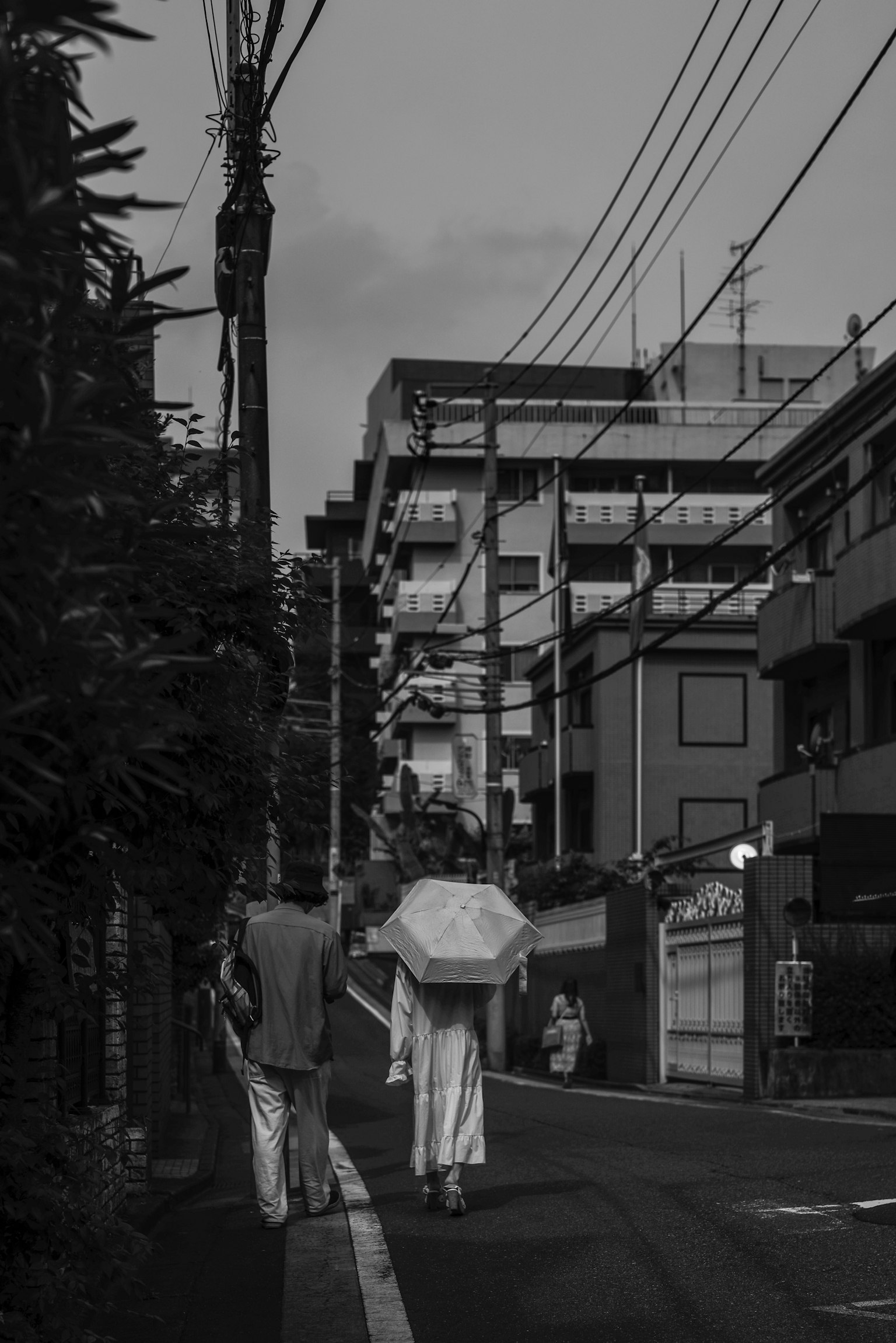 Escena en blanco y negro de una persona caminando con un paraguas blanco en la ciudad