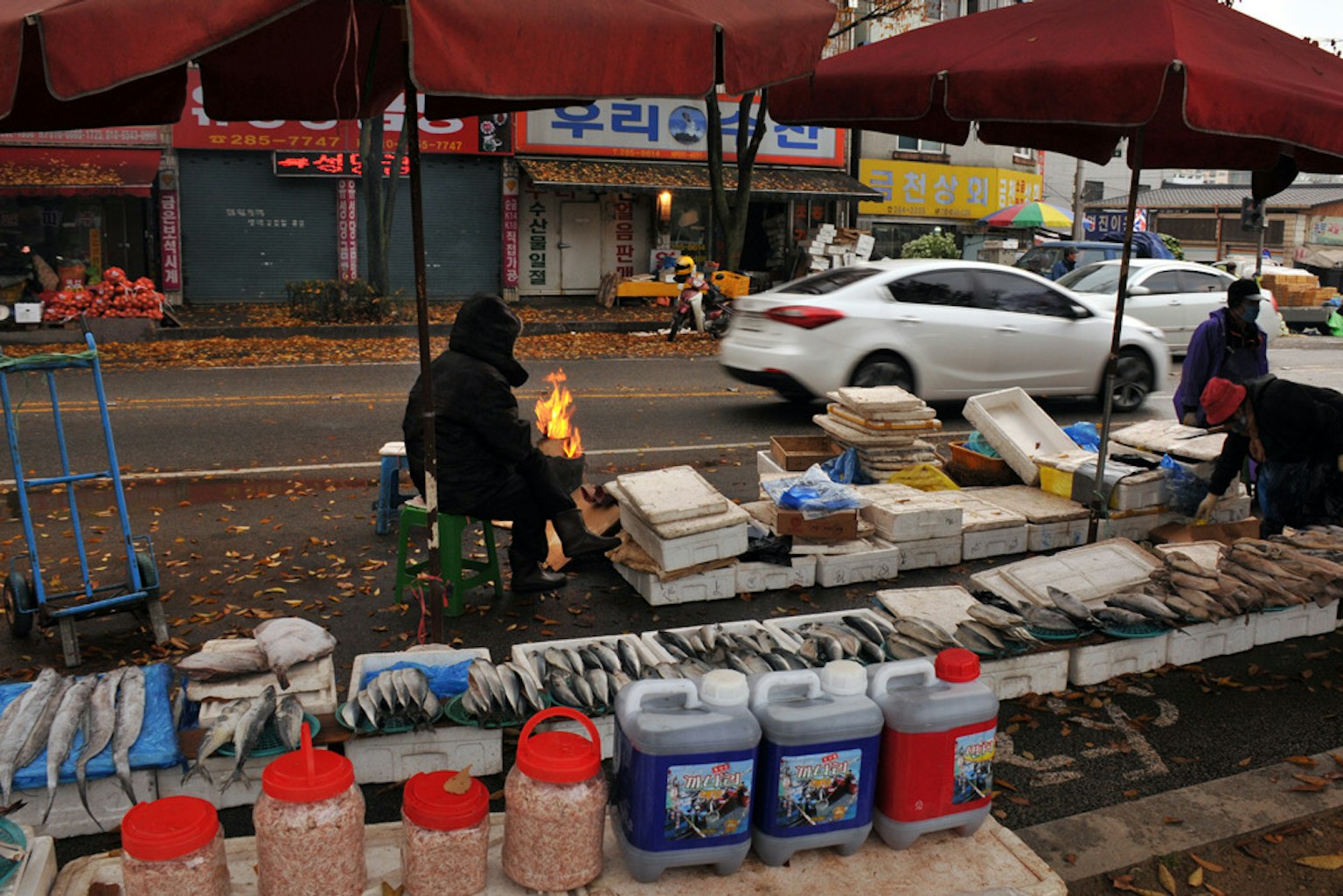 Mercado de pescado con un vendedor sentado junto a un fuego