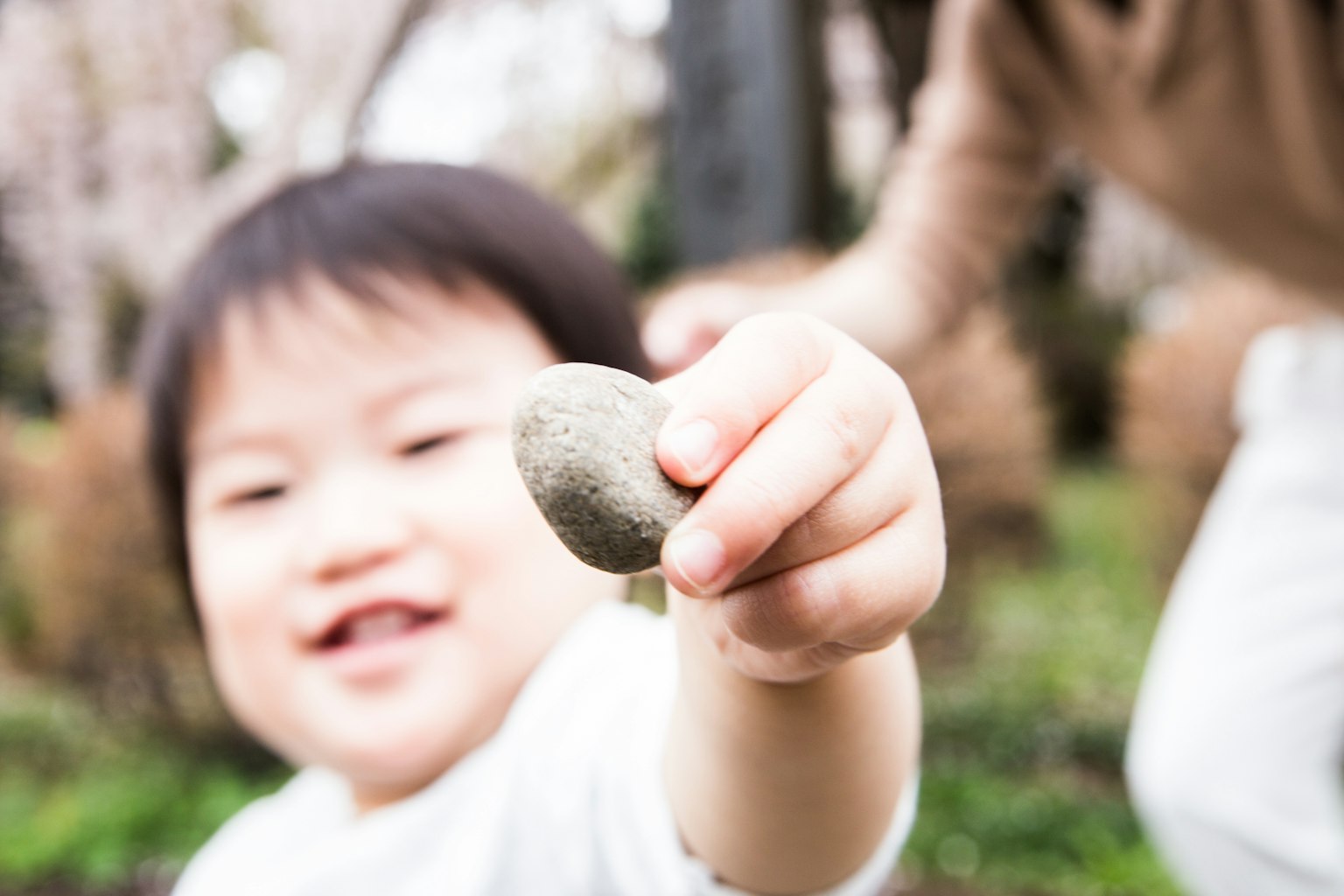 Kind lächelt und hält einen Stein in einem Park