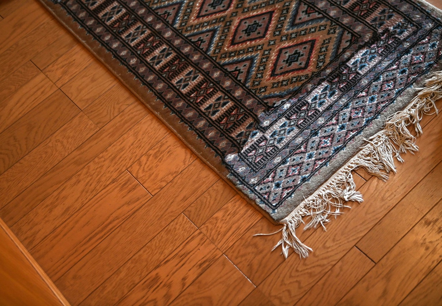Immagine che mostra una parte di un tappeto decorato su un pavimento in legno