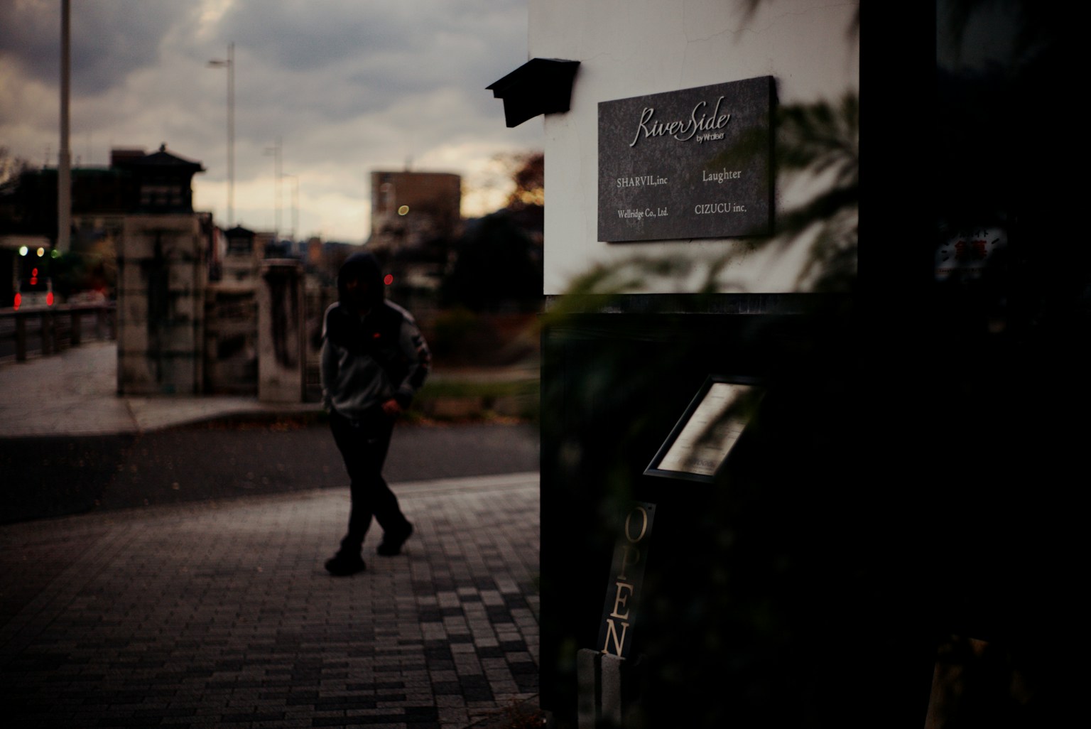 Một người đang đi bộ trên đường phố mờ với một biển hiệu có thể nhìn thấy