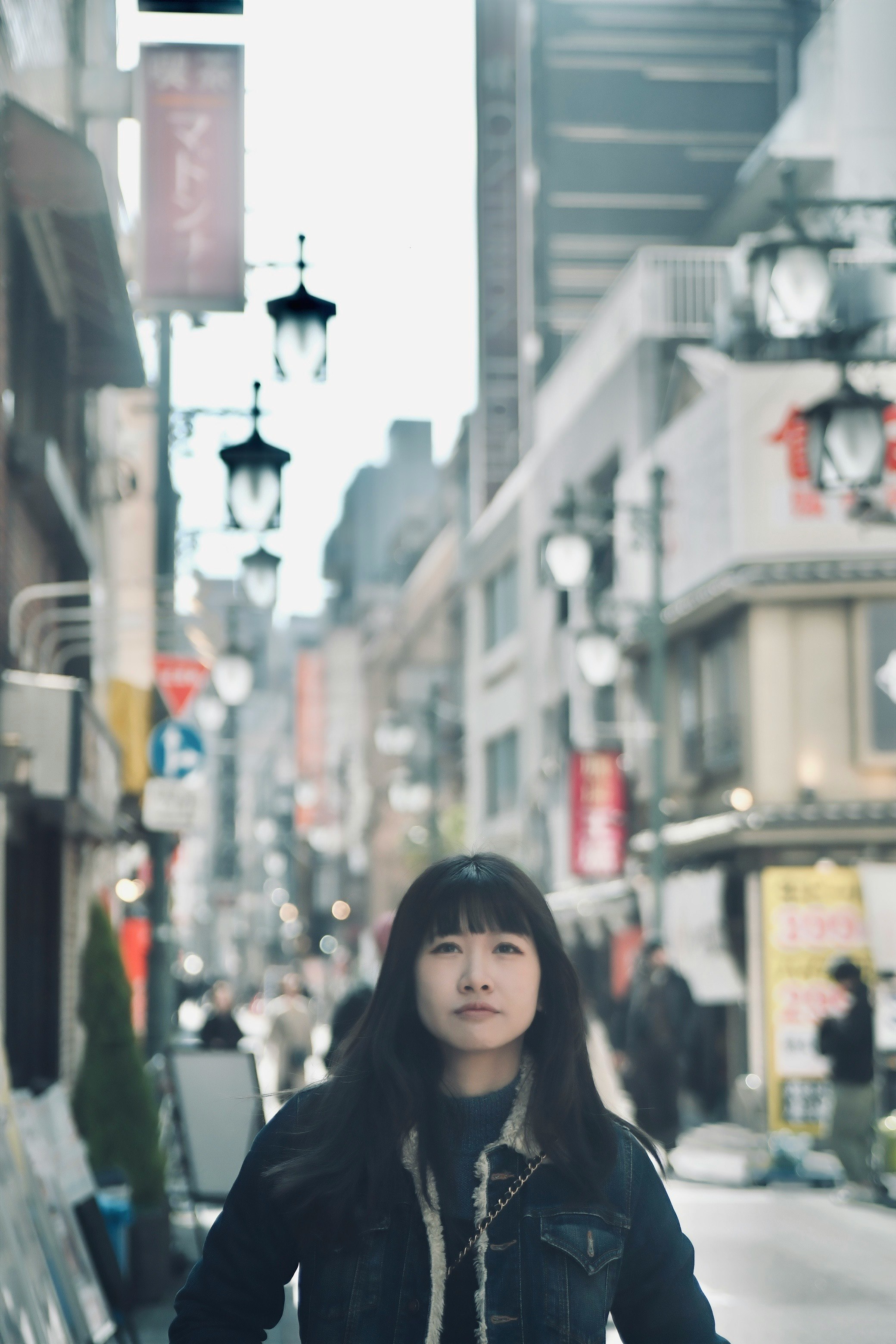 街の通りに立つ女性と周囲のランプ