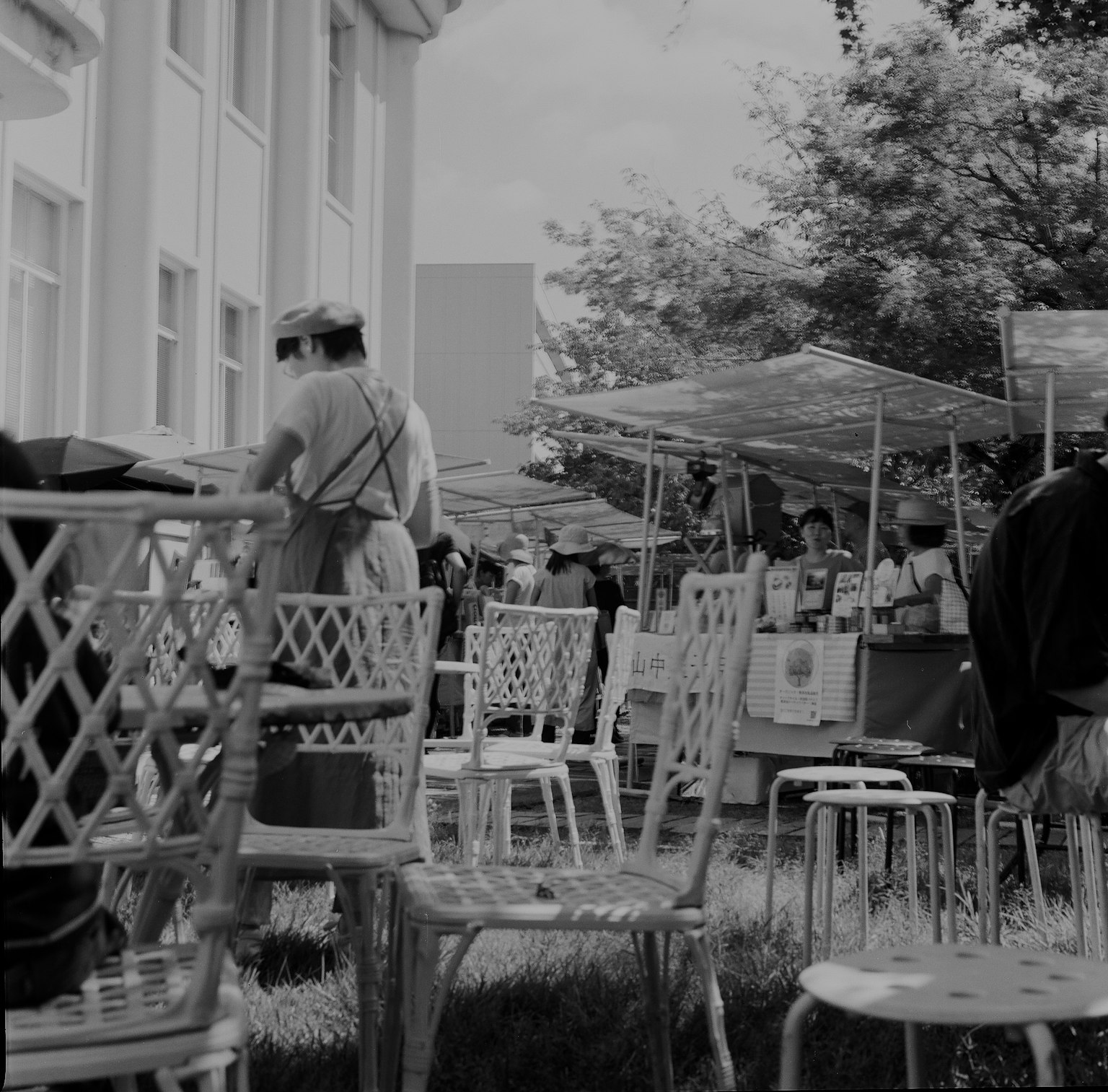 Scène de marché en plein air en noir et blanc avec des chaises et des personnes en activité
