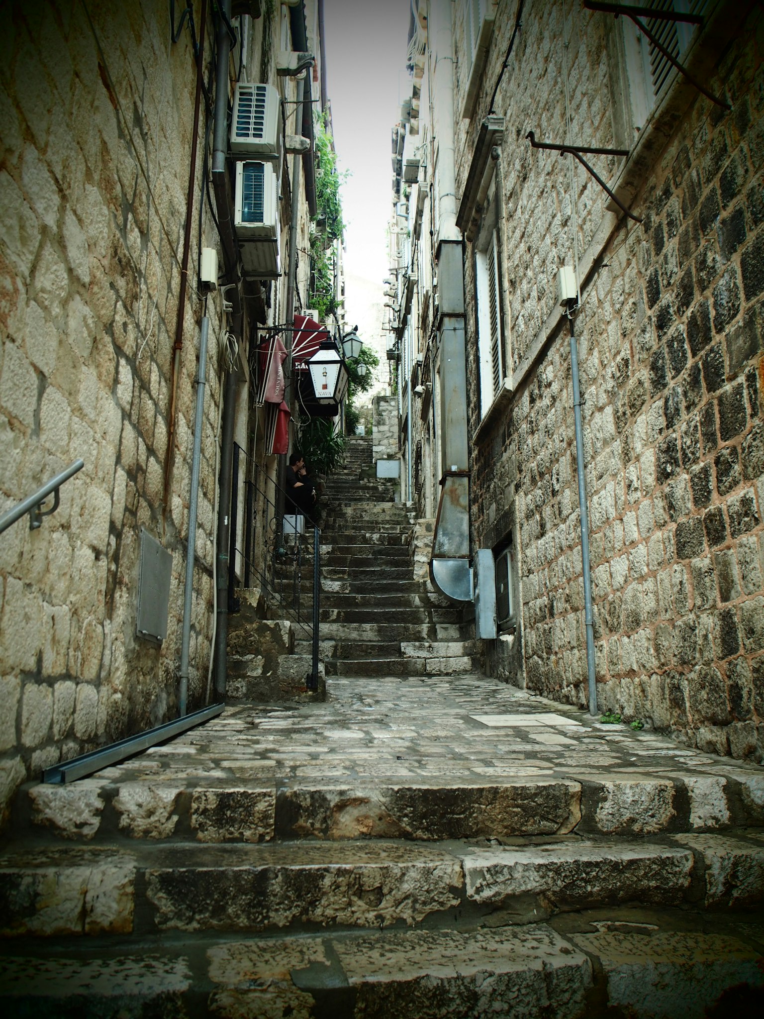 Callejón estrecho de piedra con escaleras hacia arriba