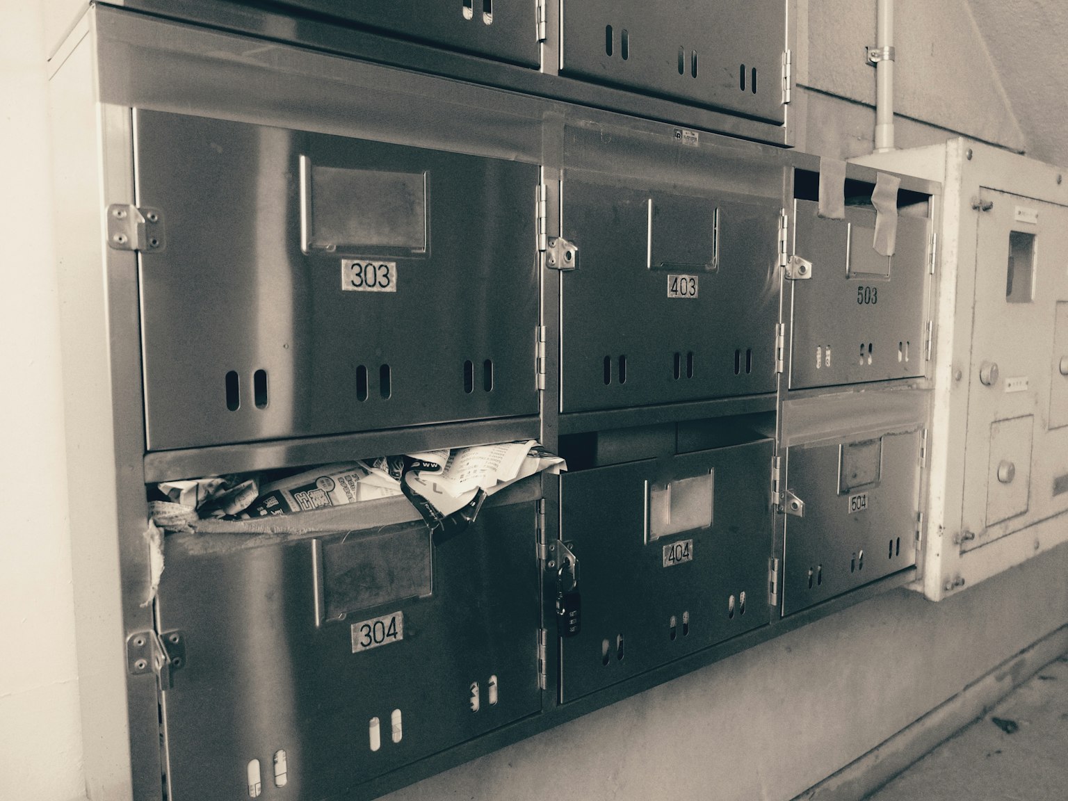 Ein Abschnitt von Metallbriefkästen an einer Wand mit überquellenden Paketen