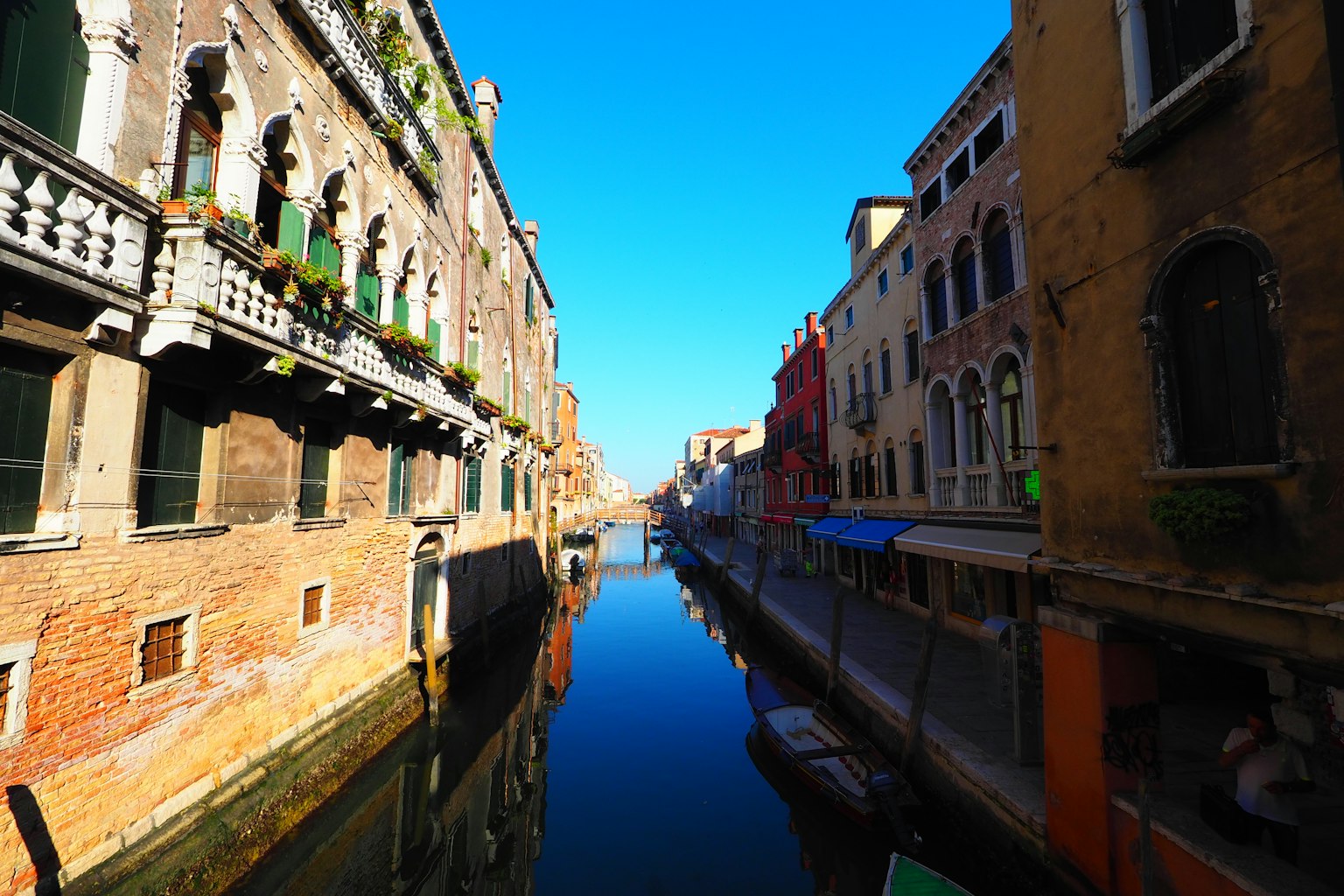 Antiguas edificaciones venecianas a lo largo de un canal tranquilo bajo un cielo azul claro