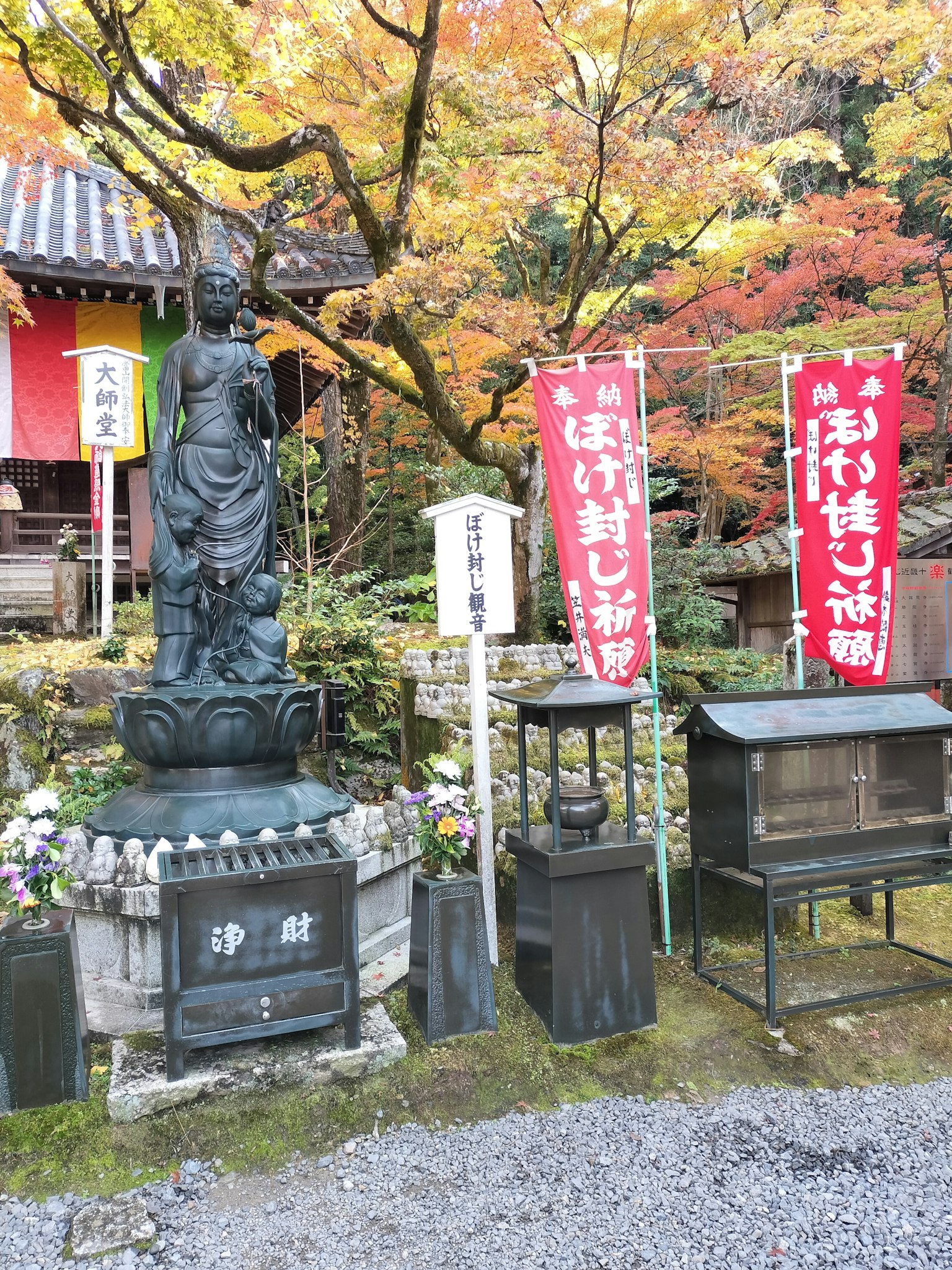 A statue surrounded by autumn foliage and red banners