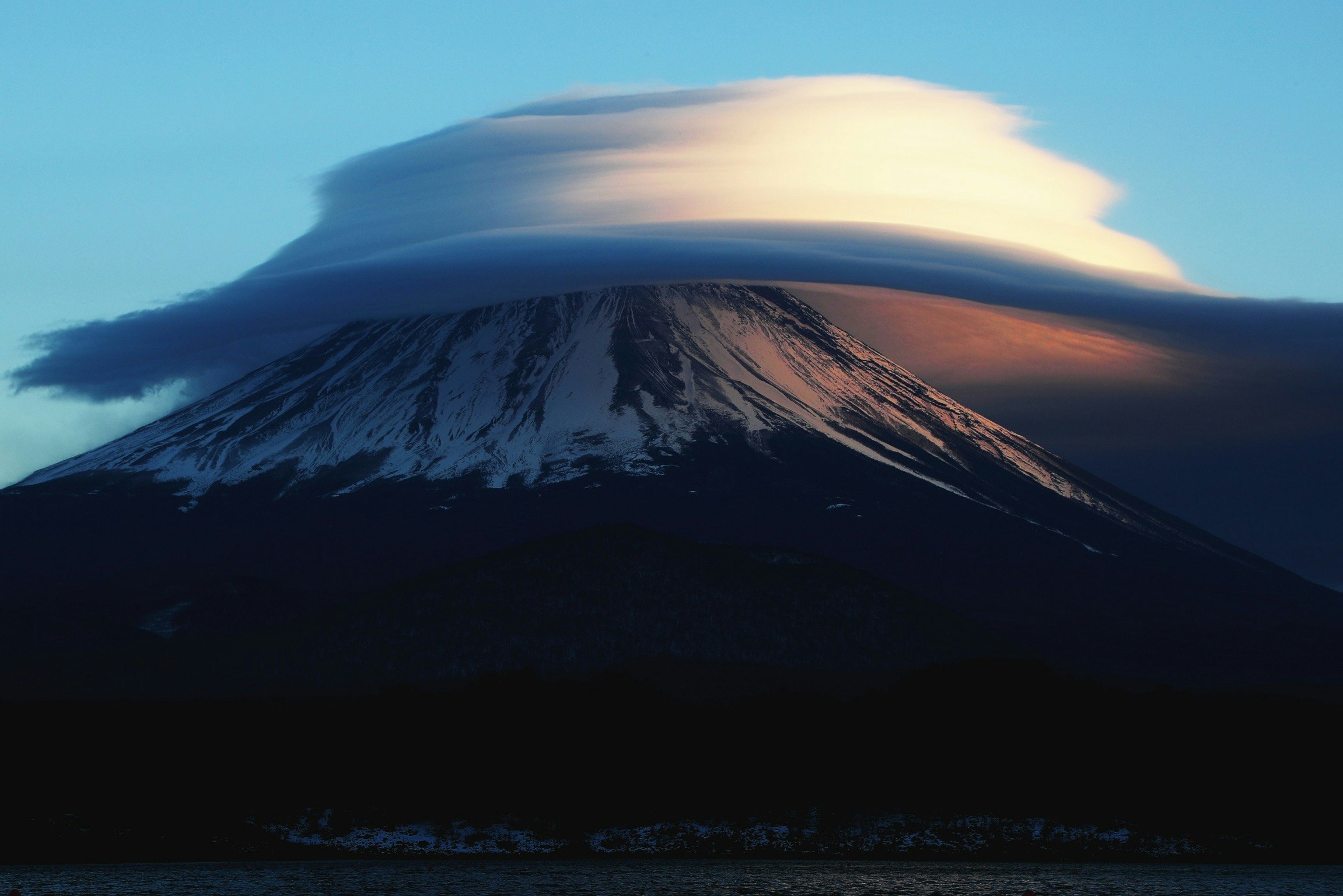 夕暮れの噴煙を上げる火山と海岸の風景