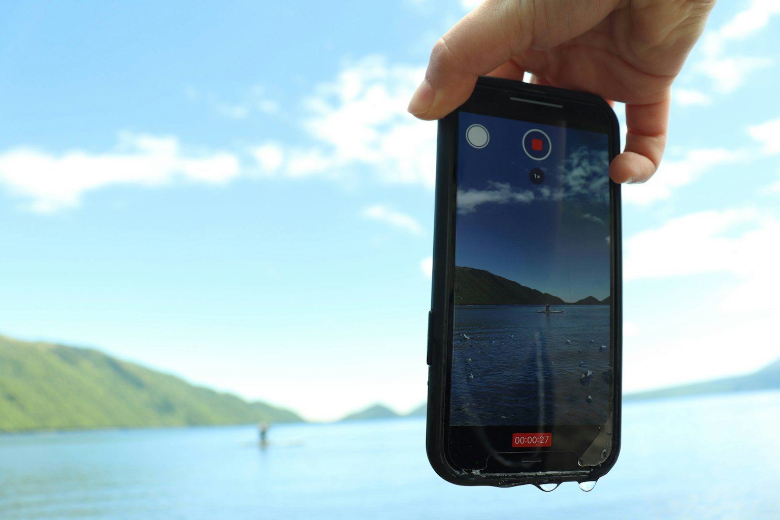 Uno smartphone tenuto in mano che mostra una vista panoramica del lago