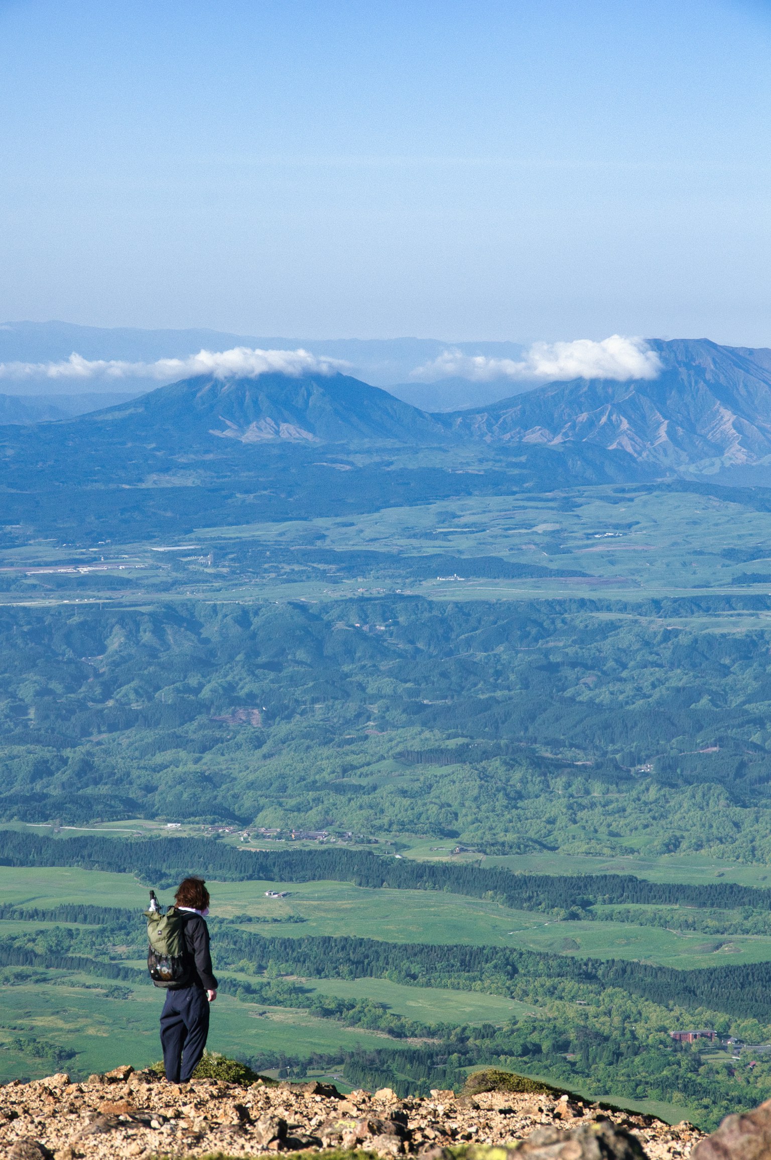 Caminante en la cima de una montaña con vista a un paisaje verde