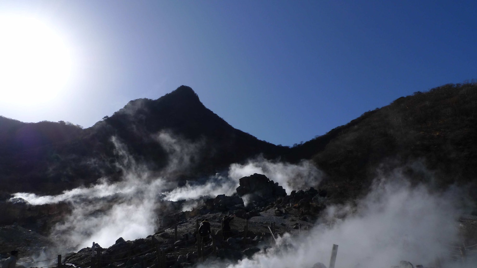 蒸汽上升的山景，蓝天，太阳，火山活动的迹象