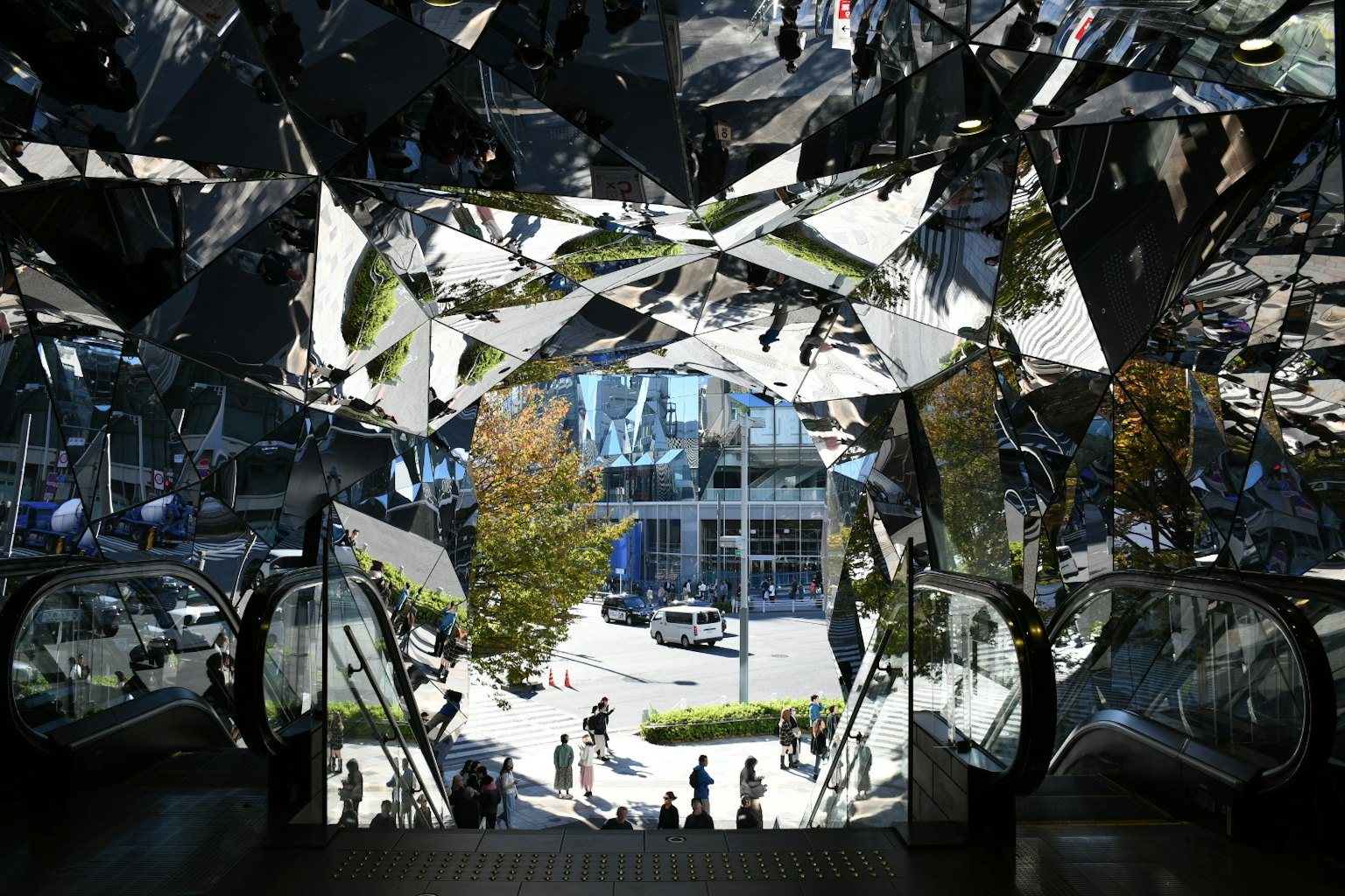 Blick auf eine Stadtszene mit Menschen durch eine reflektierende Spiegelstruktur