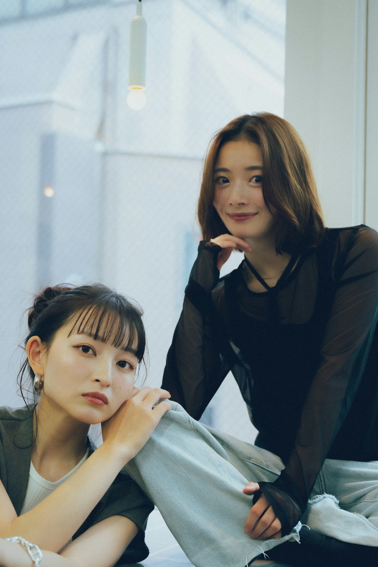 Two women posing near a window in natural light showcasing fashion style