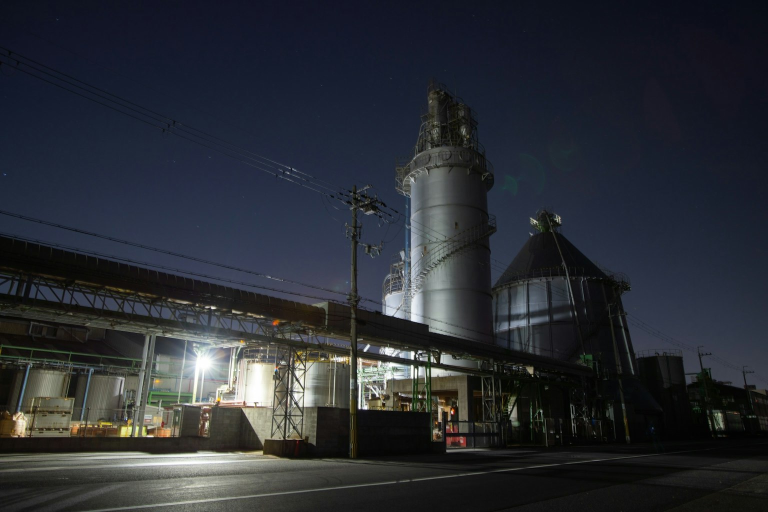 Vista esterna di una fabbrica di notte con silos visibili