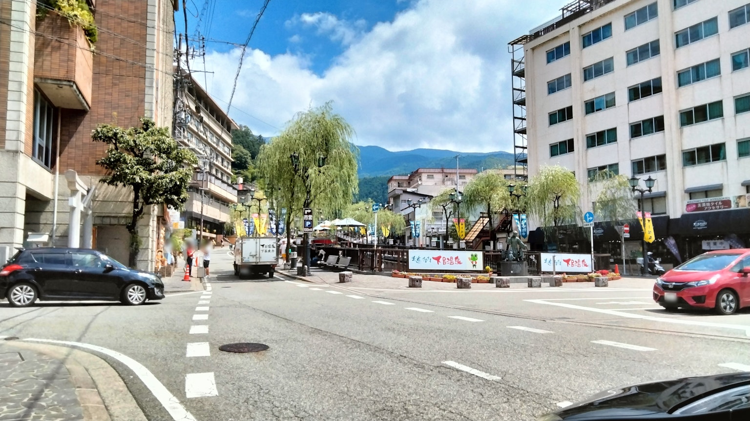 City street view with cars and buildings featuring green trees and blue sky