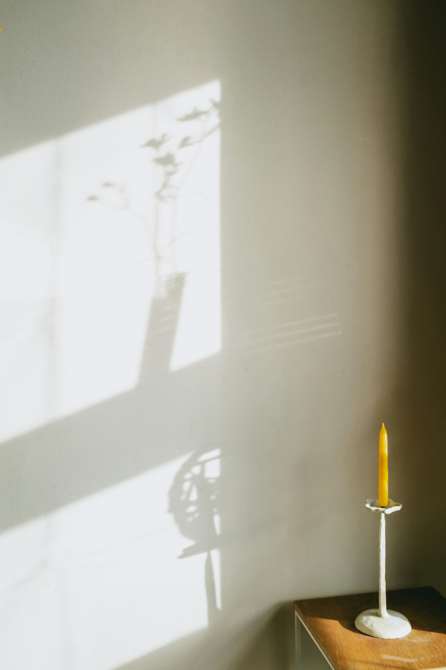 Schatten an der Wand mit einer gelben Kerze auf einem Tisch