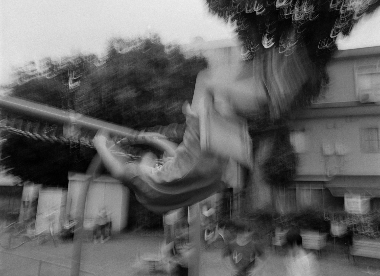 Foto borrosa en blanco y negro de un niño jugando en un columpio