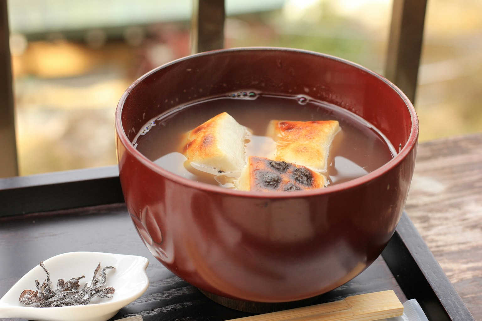 Tazón rojo con sopa de miso y pasteles de arroz a la parrilla