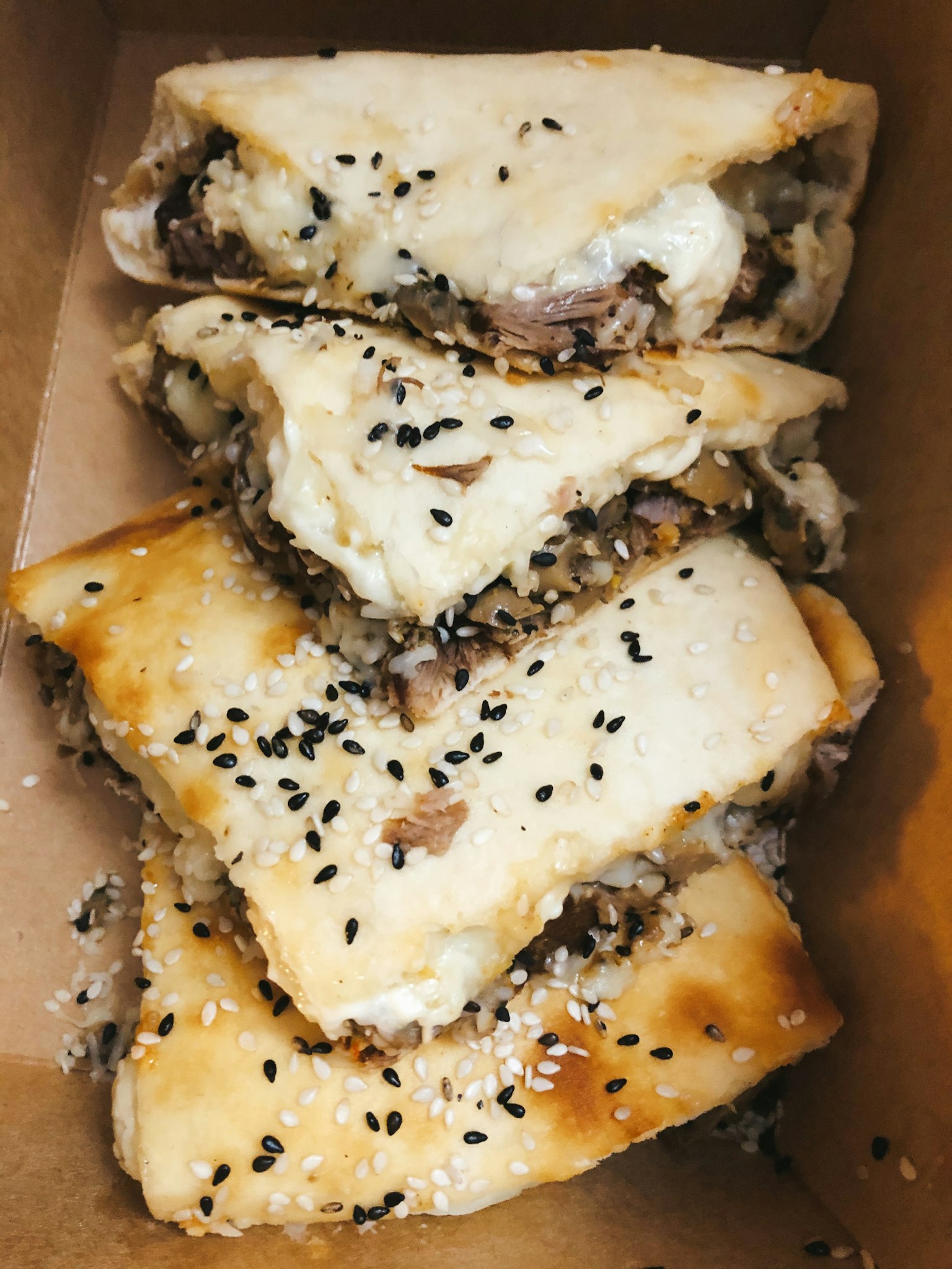 Flatbread filled with meat and topped with black sesame seeds