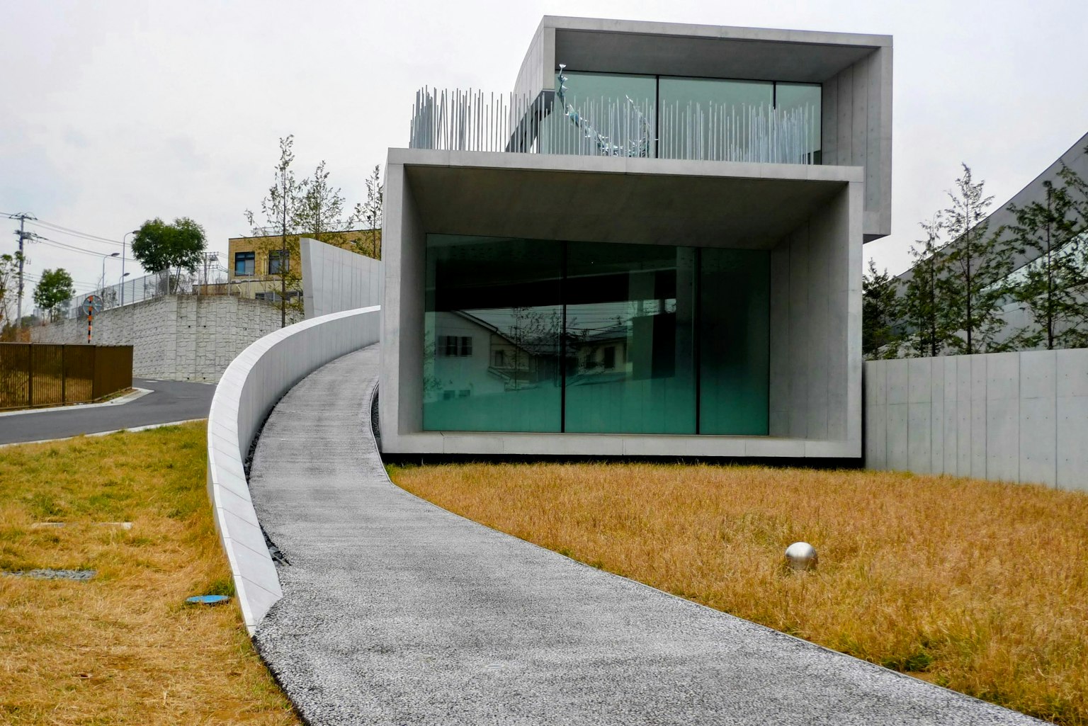 Casa moderna in cemento con un vialetto curvo e prati verdi