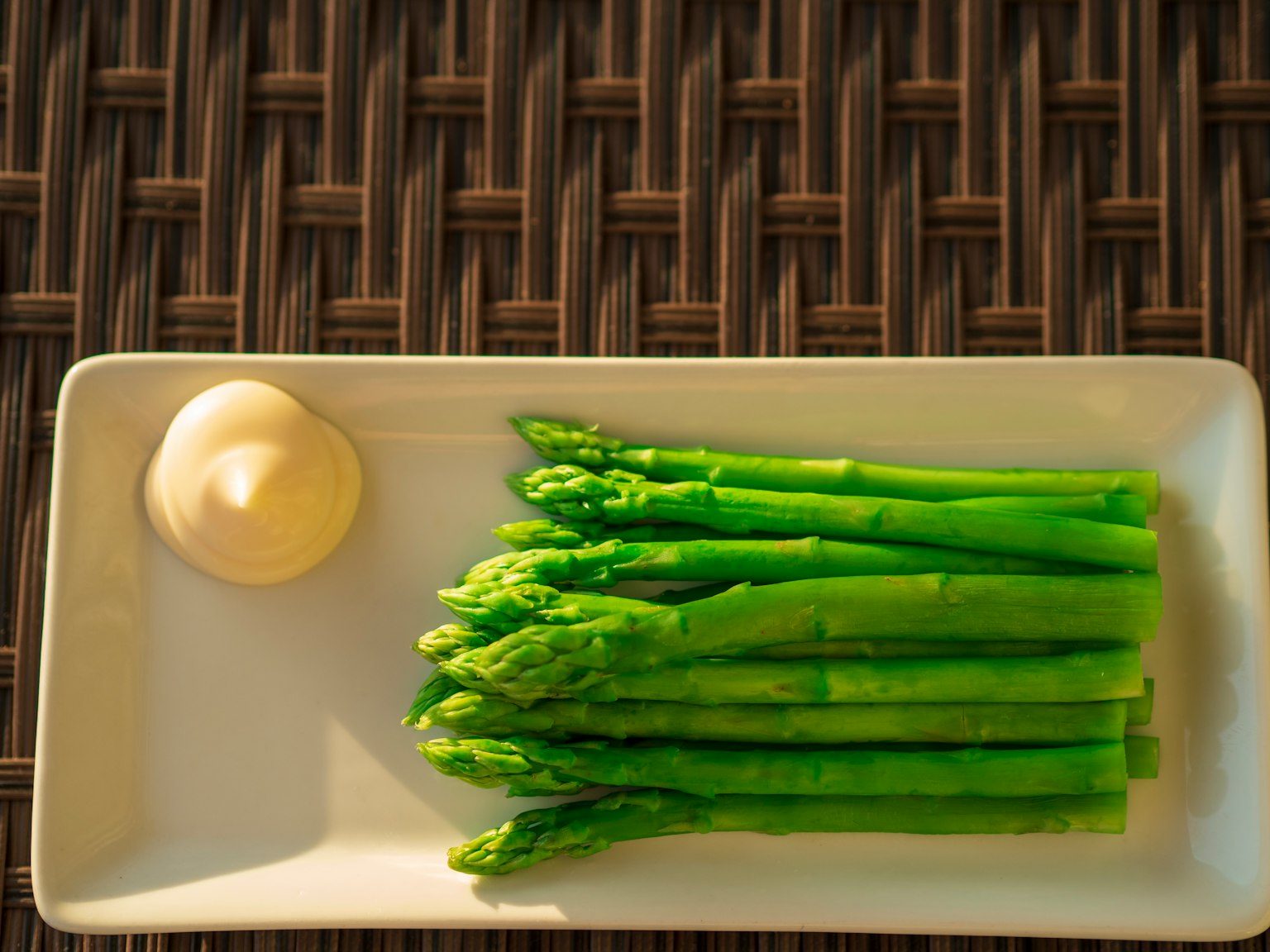 Espárragos verdes frescos en un plato blanco con mayonesa