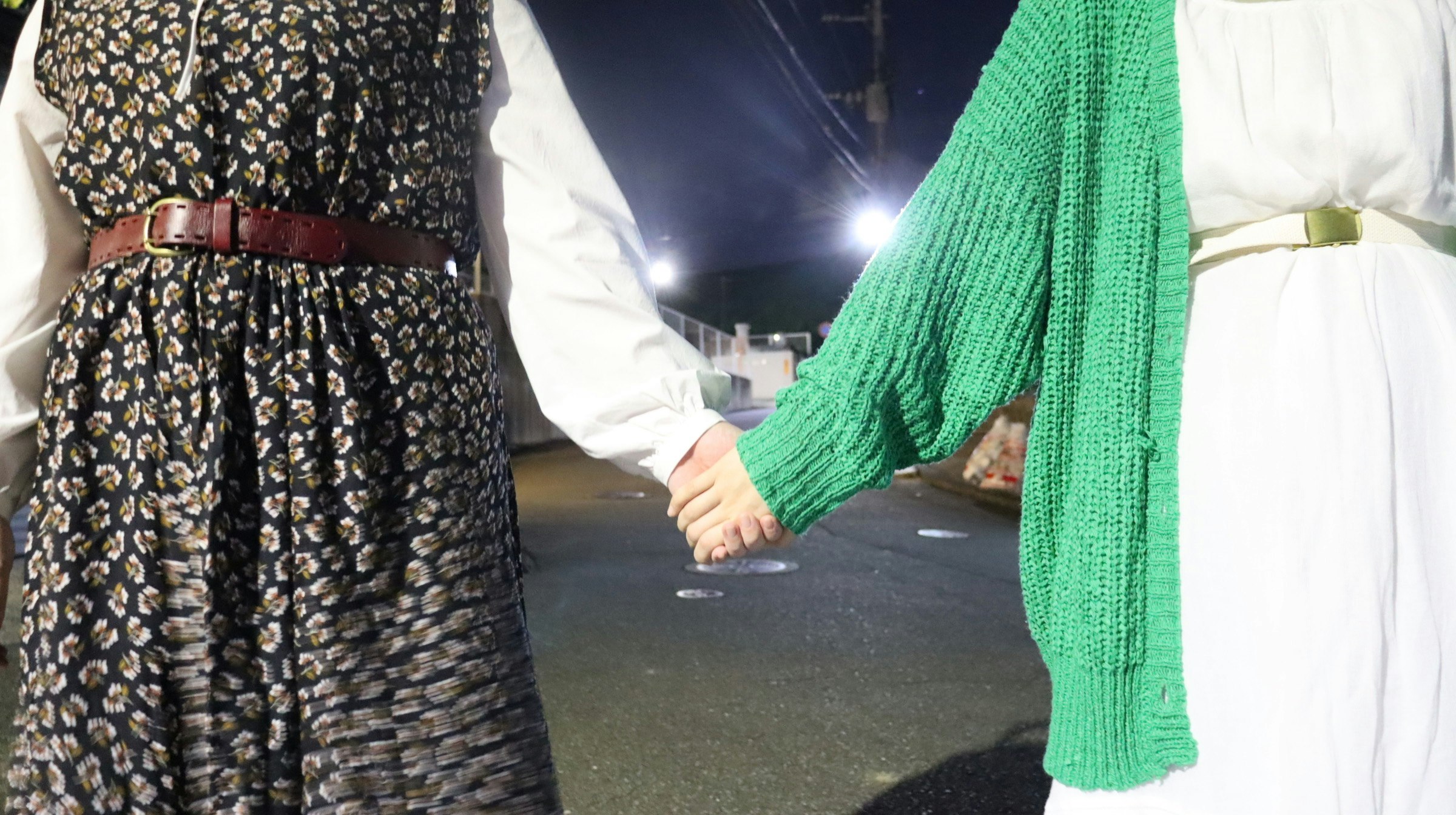 夜の屋外で手をつなぐ2人の人物