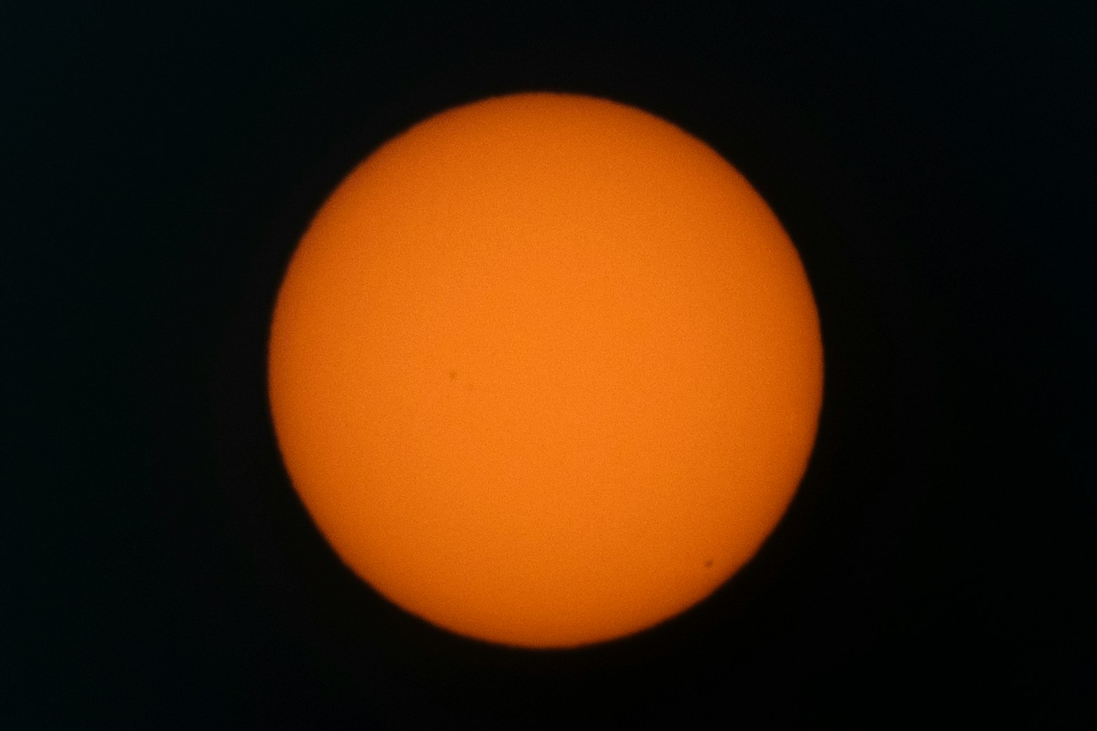黒い背景に浮かぶオレンジ色の太陽のような円形天体
