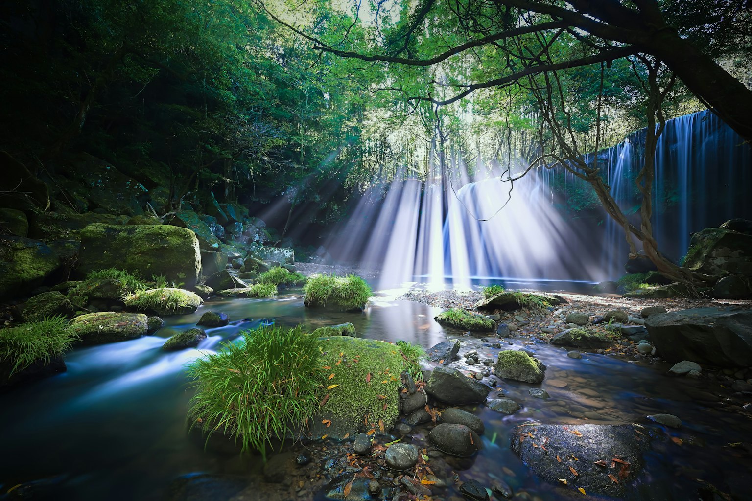 Wasserfall in einem üppigen grünen Wald mit Lichtstrahlen, die durch das Wasser scheinen