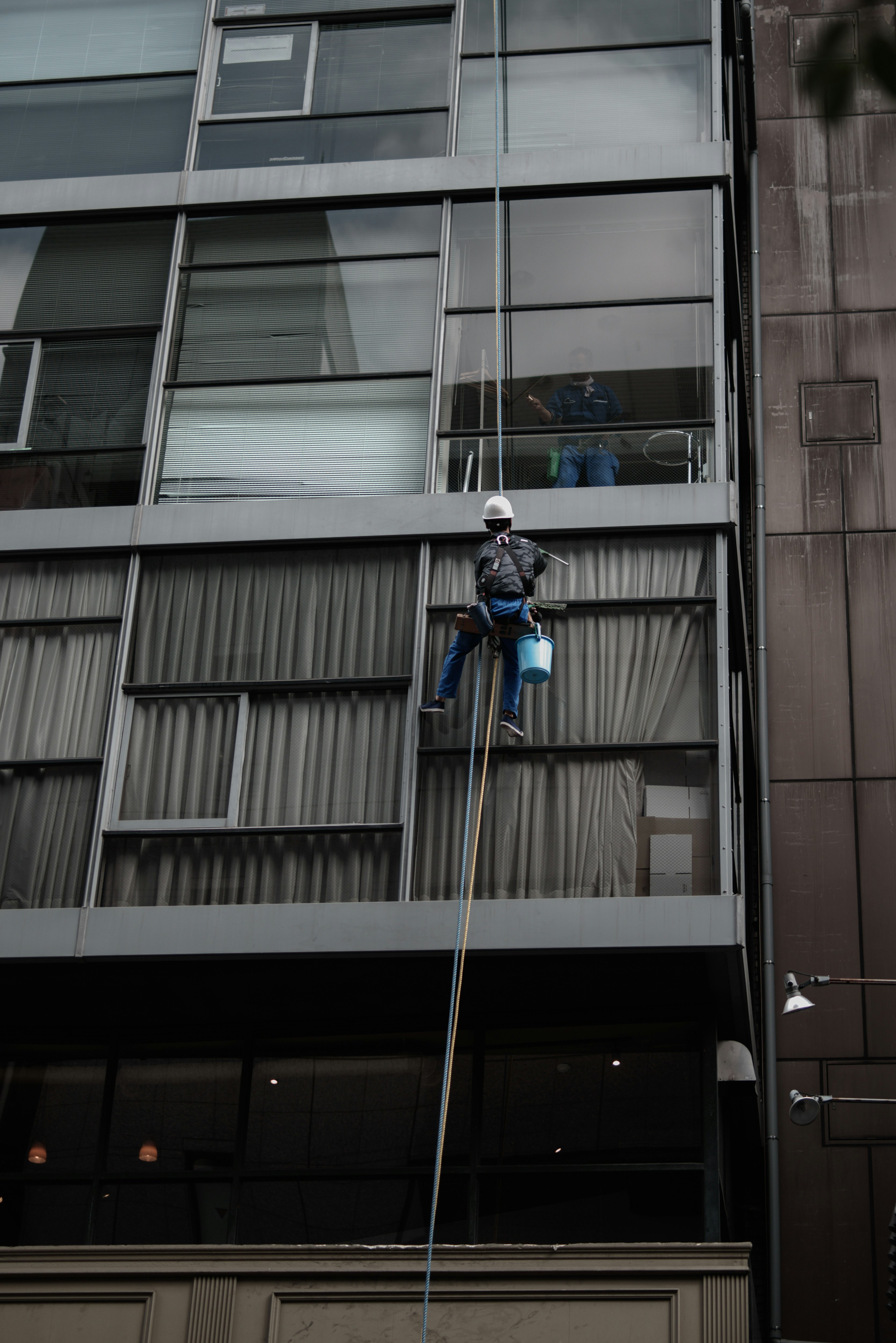 Fensterreiniger in Seiltechnik an der Außenfassade eines Gebäudes