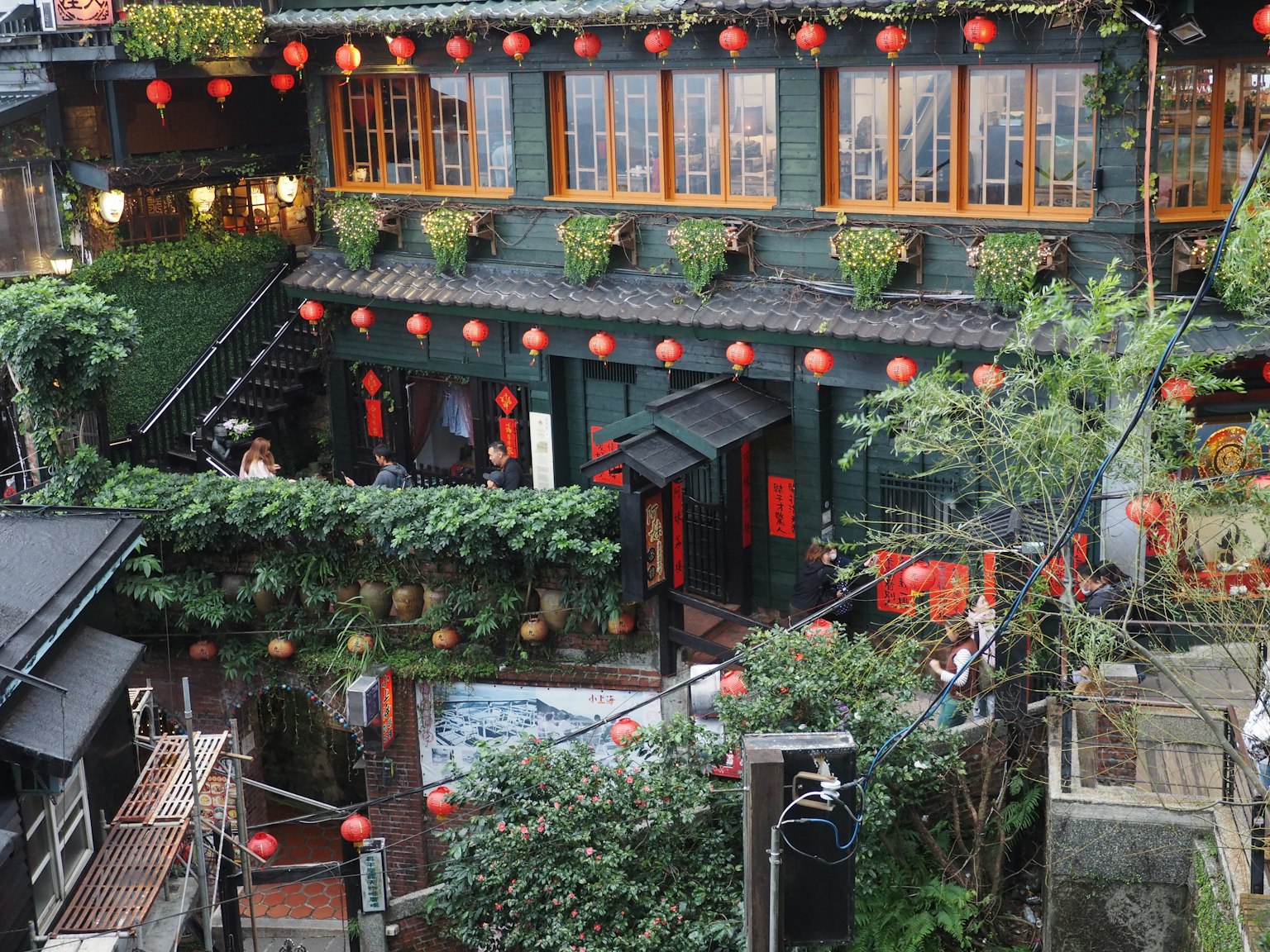 Edificio tradicional con plantas verdes y faroles rojos en un jardín