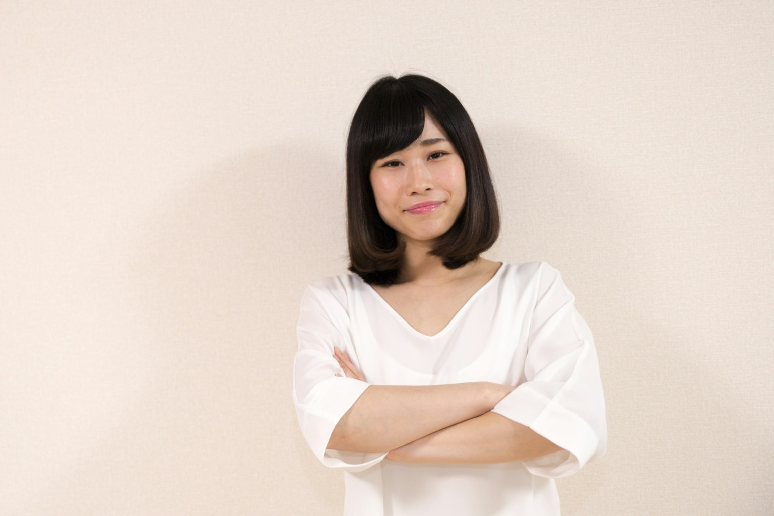 A woman in a white shirt with crossed arms smiling