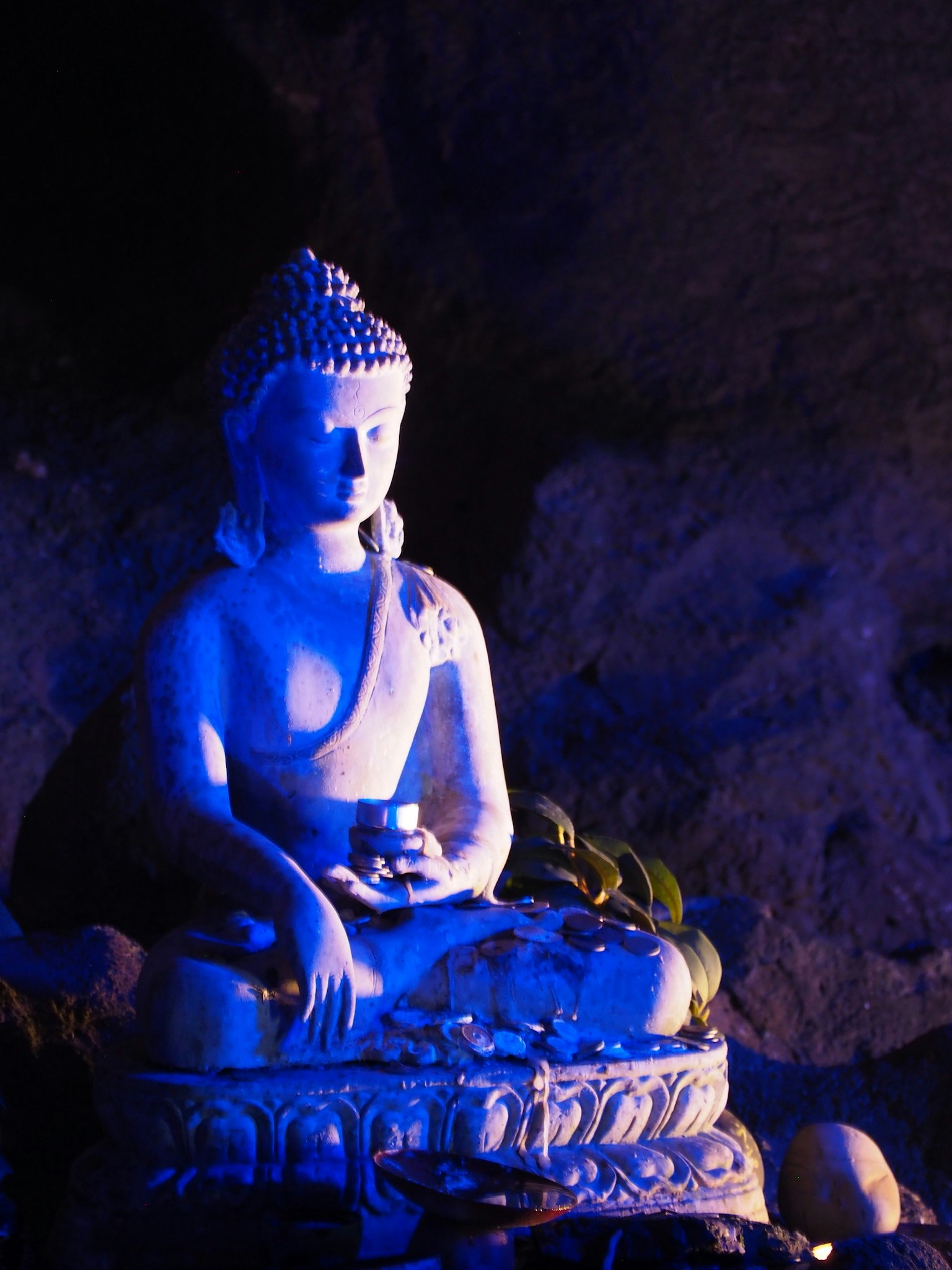 Eine von blauen Licht beleuchtete Buddha-Statue sitzt ruhig