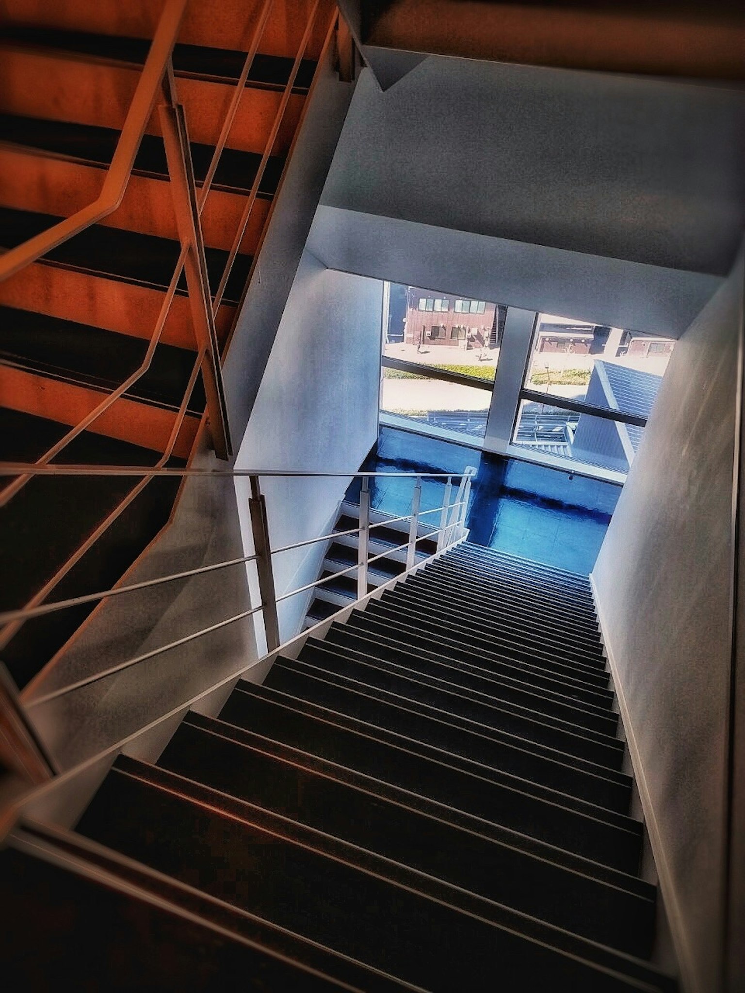 Blick von unten einer Treppe mit Licht, das durch ein Fenster strömt und eine blaue Fläche zeigt