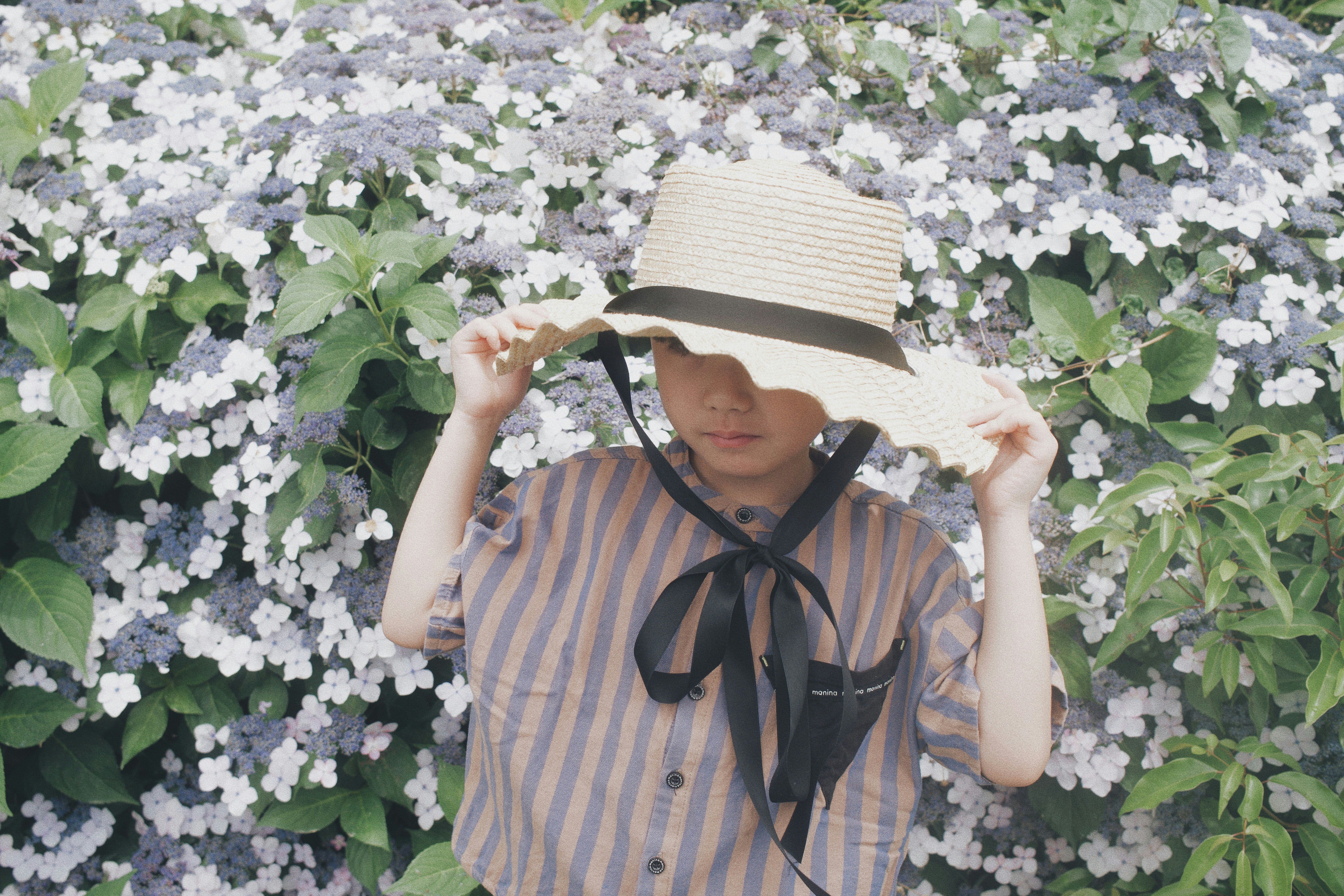 花畑で麦わら帽子をかぶった子ども