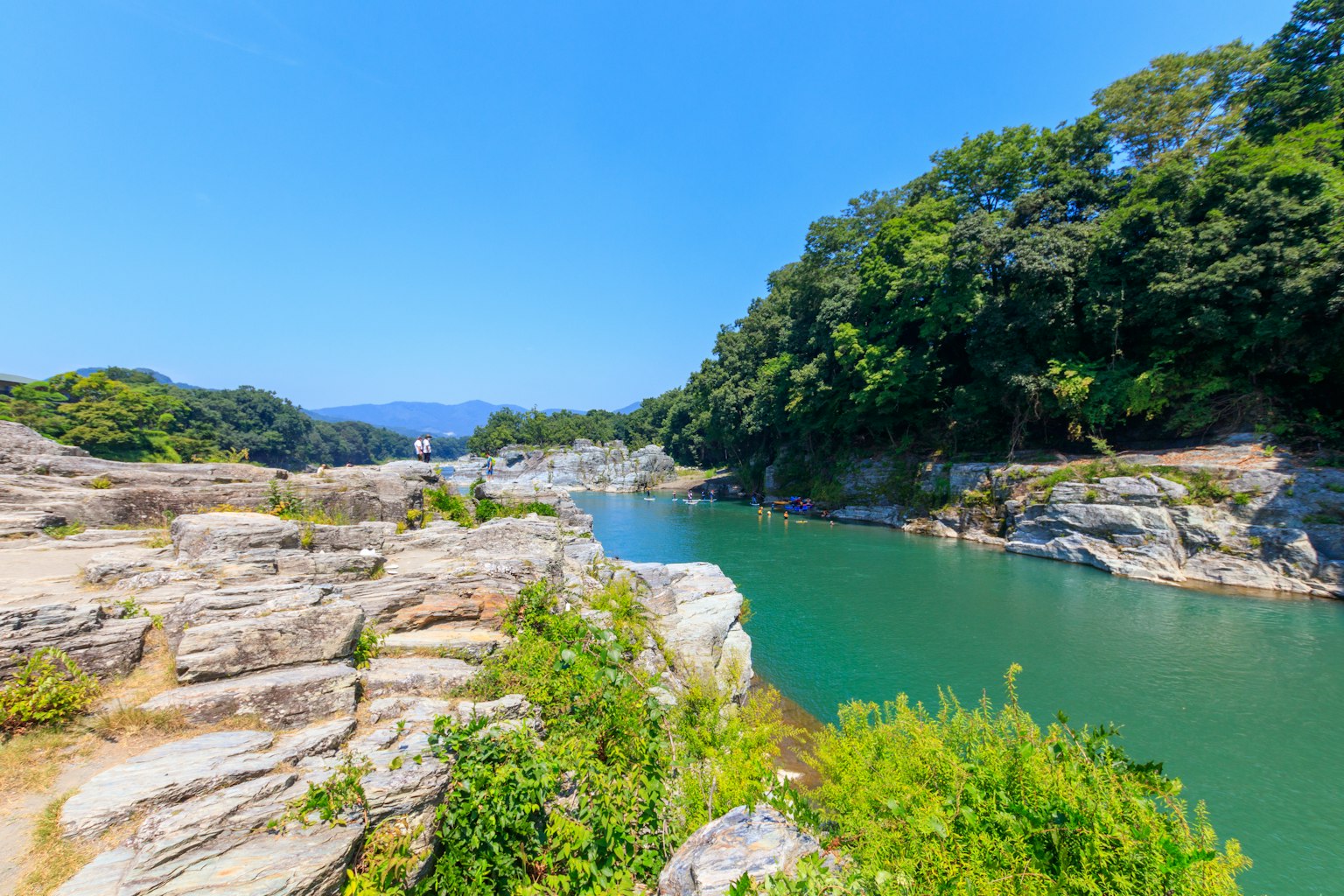 藍天之下，四周環繞著郁郁蔥蔥的綠色植被和岩石的河流美景