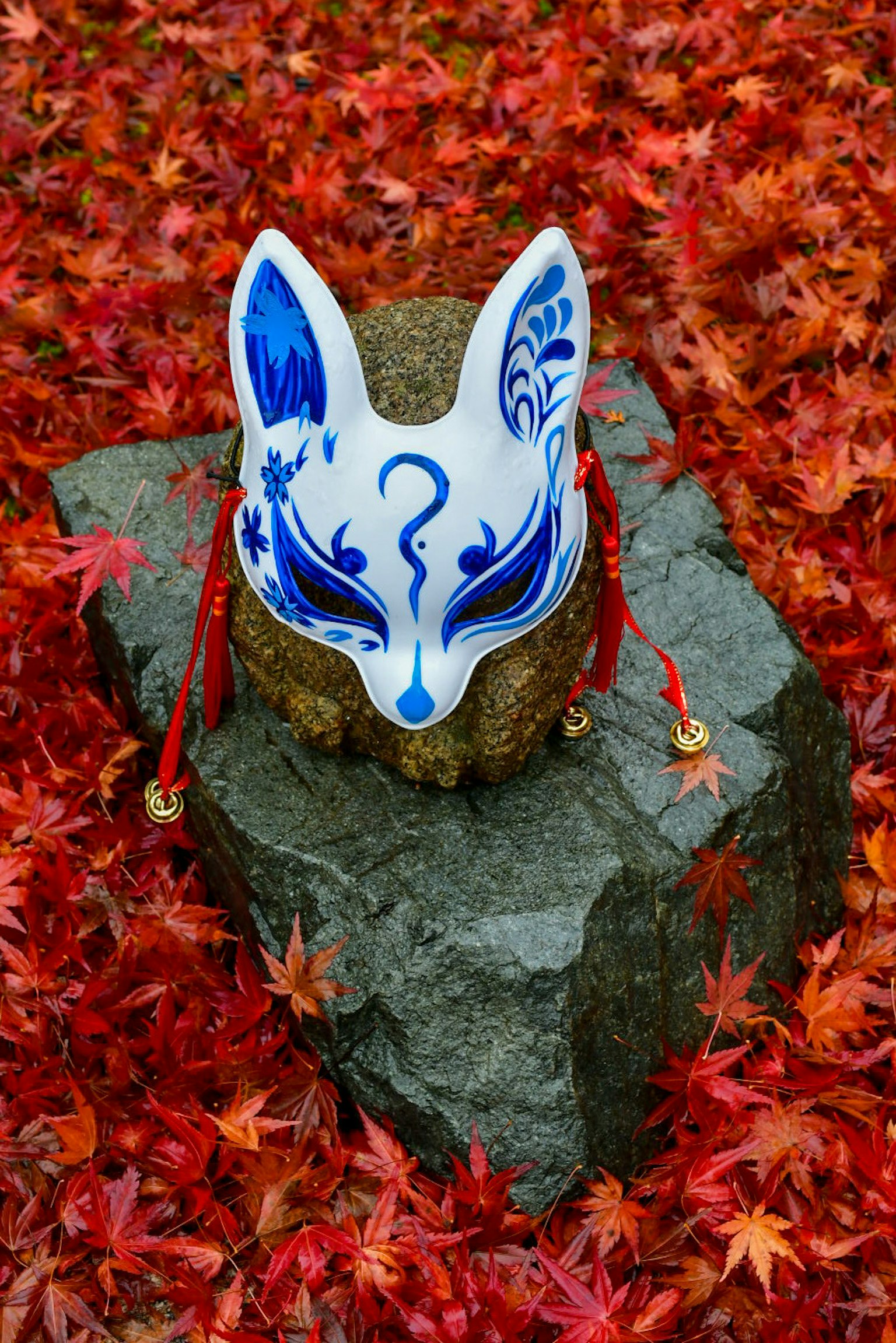 Fox mask with blue patterns placed on red maple leaves
