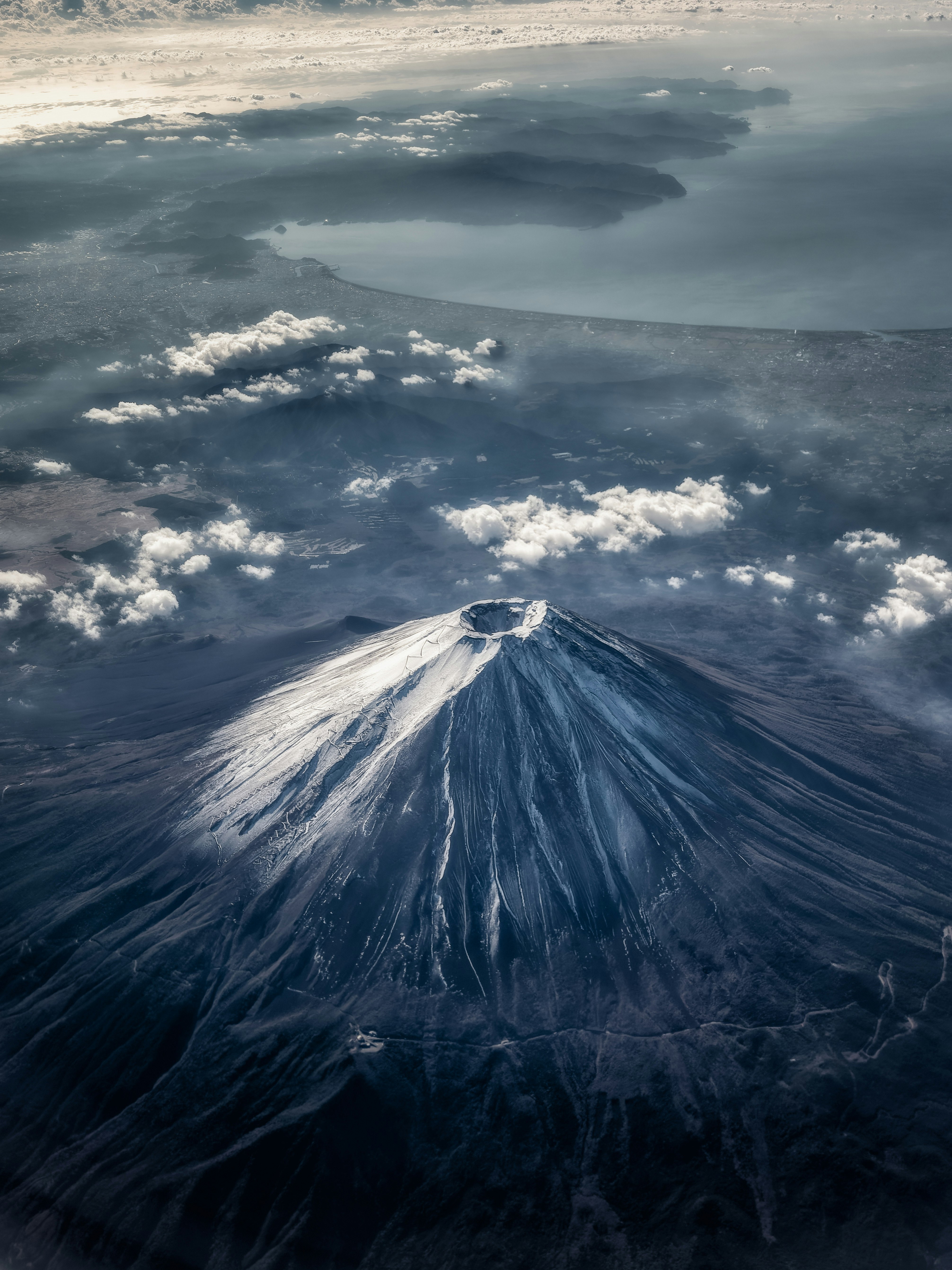 噴煙を上げる火山と海に広がる雲の上空景観