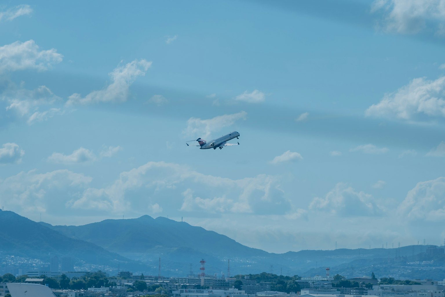 Airplane taking off against a blue sky and mountain backdrop