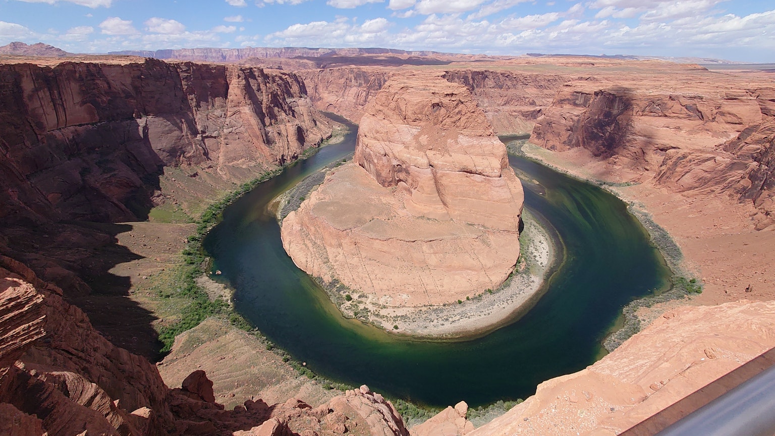 Panoramablick auf Horseshoe Bend mit einem grünen Fluss und roten Felsformationen