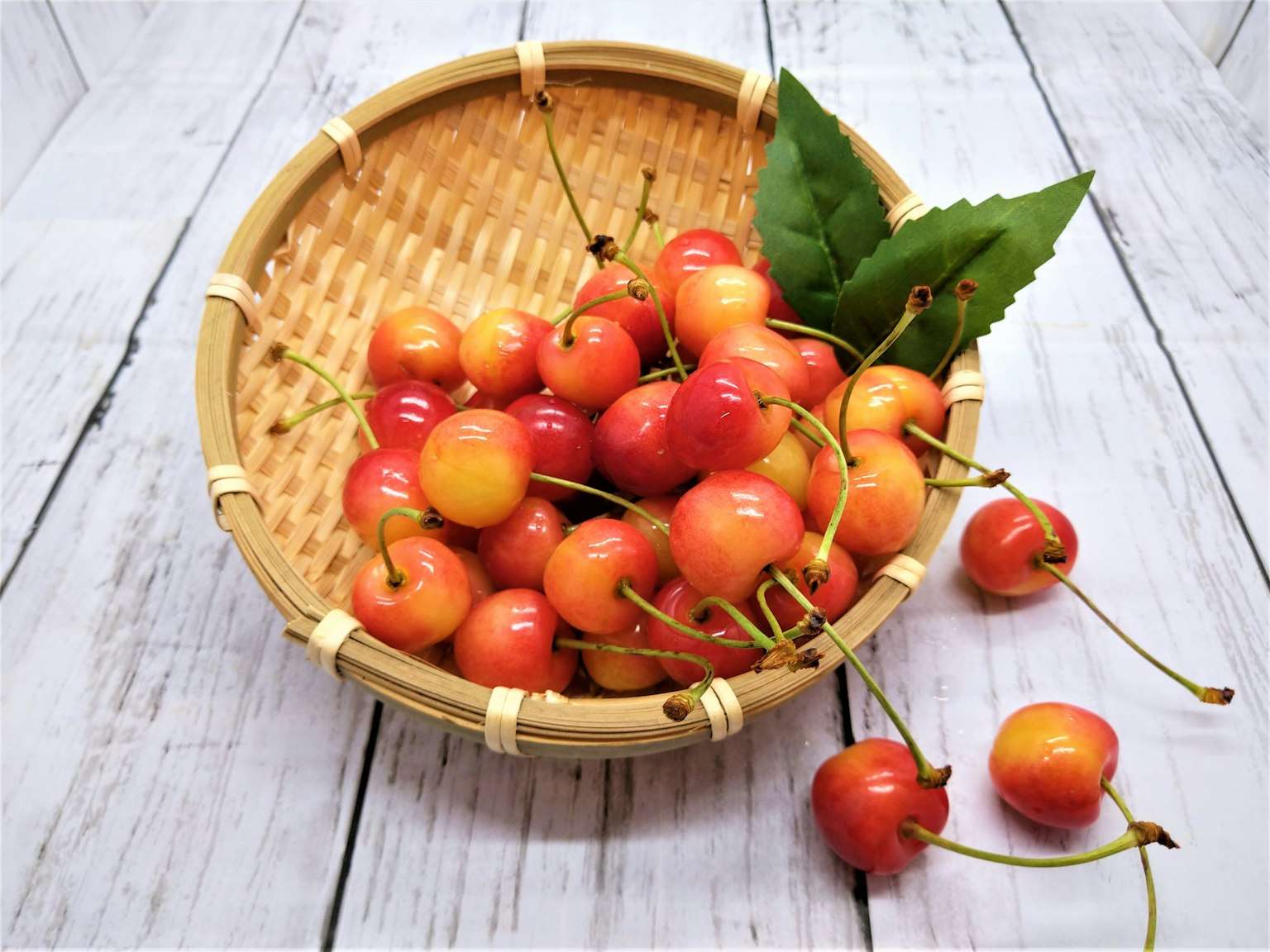 Vibrant cherries in a woven basket with green leaves