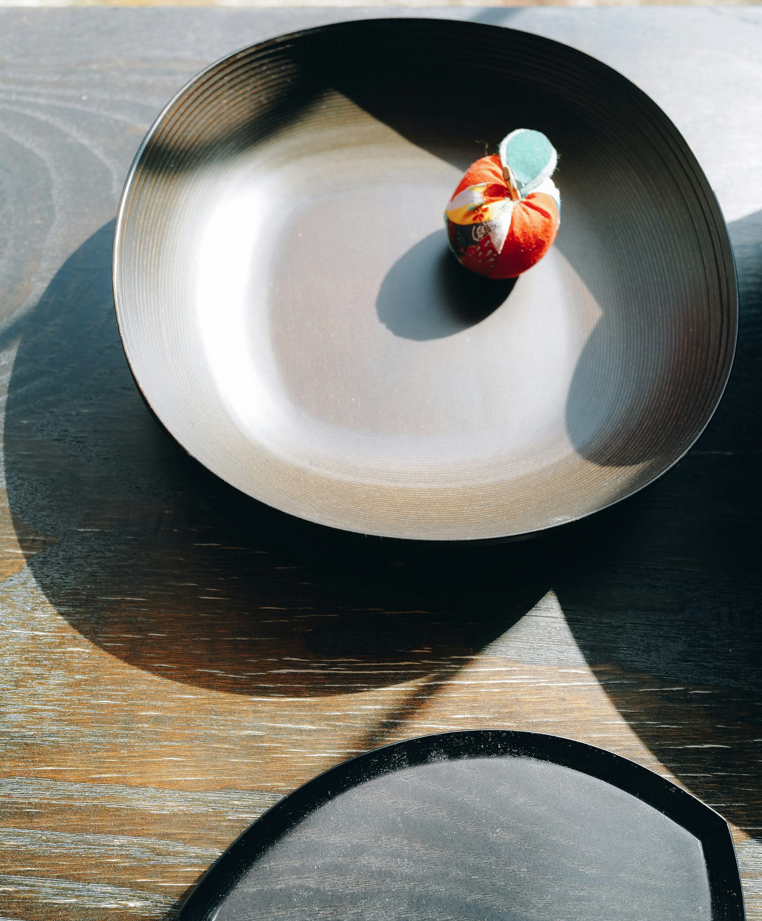 un petit fruit décoratif rouge placé sur un plat noir