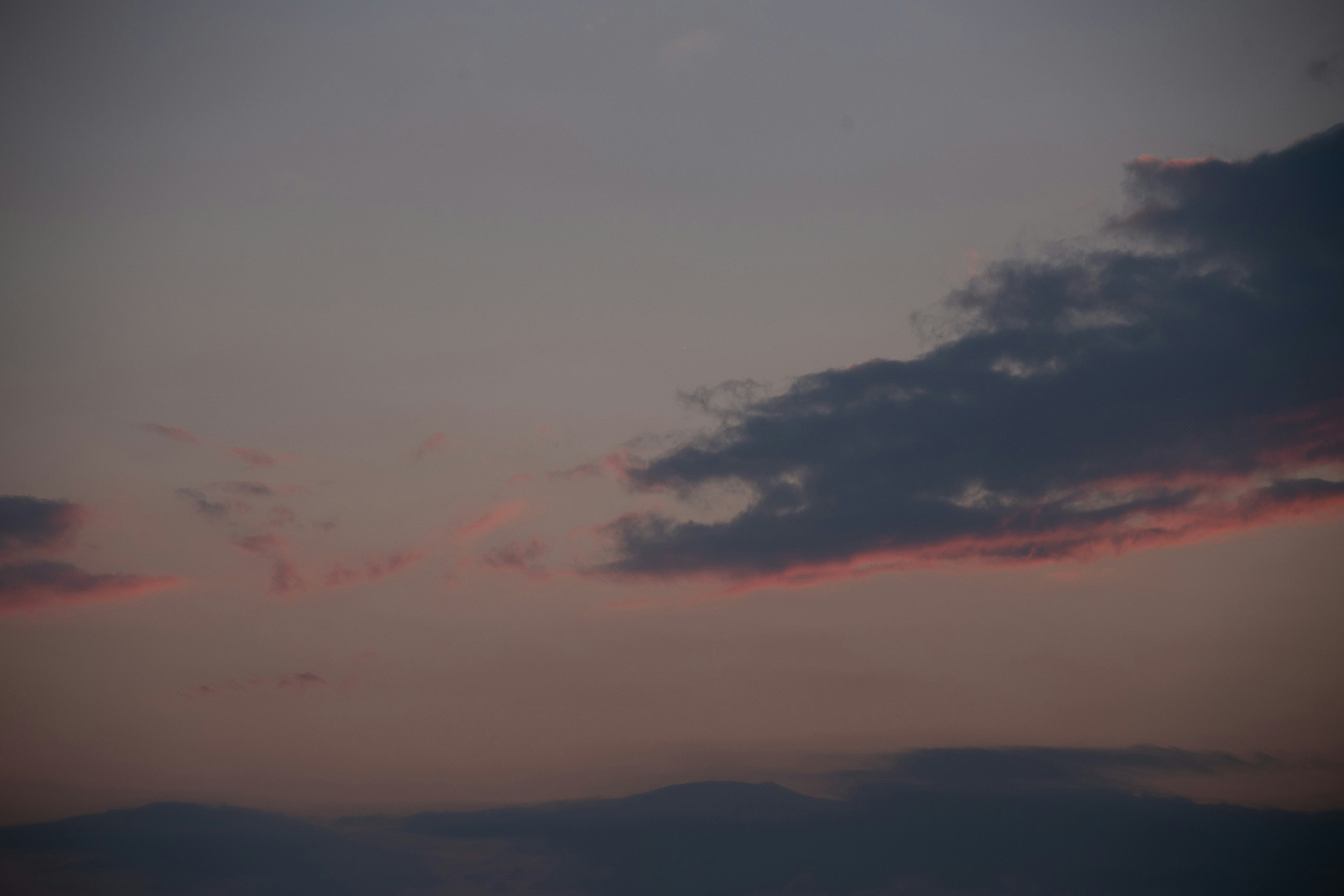 Dämmerungshimmel mit Wolken und fernen Bergsilhouetten