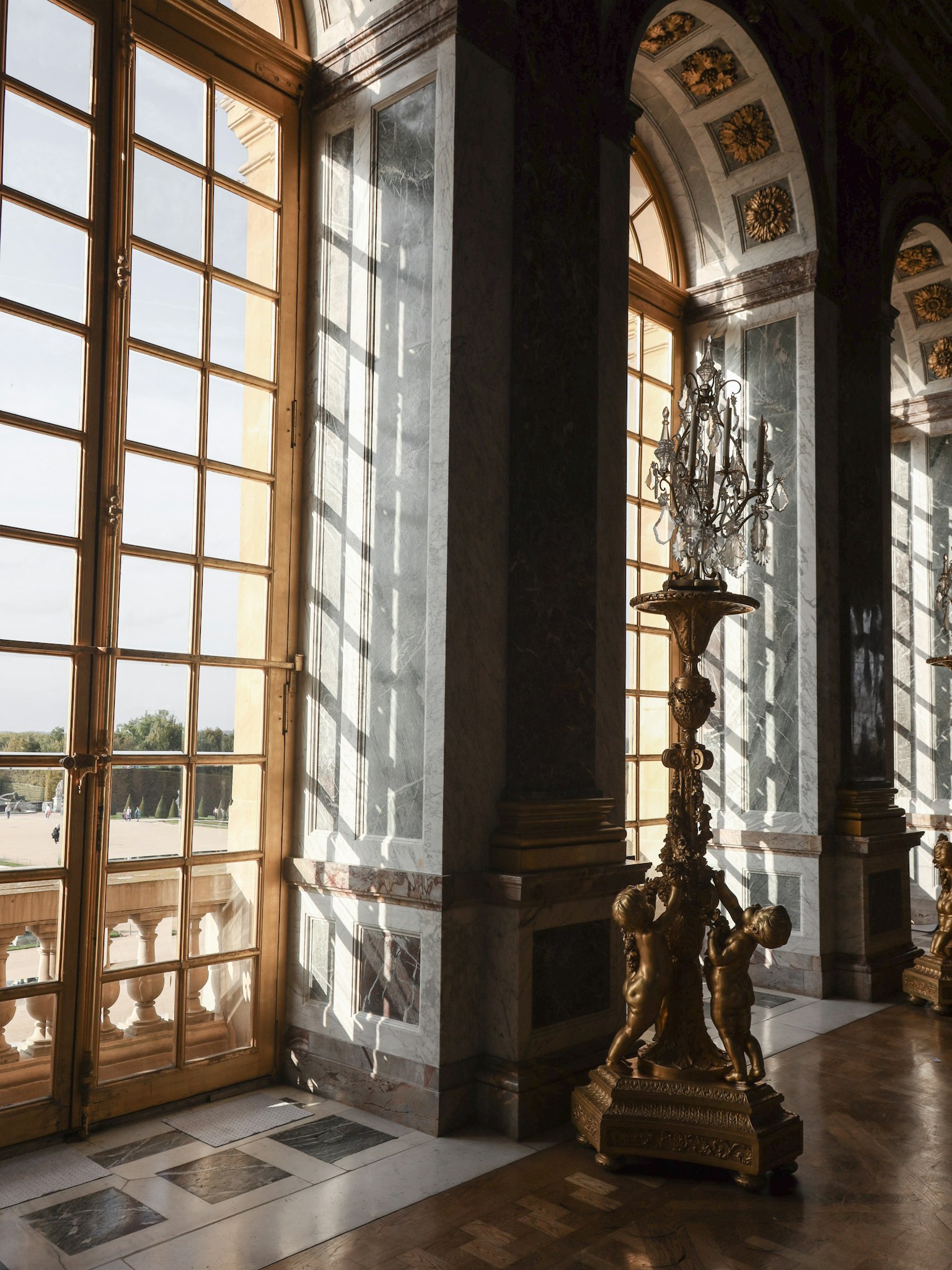 Interior Istana Versailles dengan lampu gantung mewah jendela besar dan dekorasi rumit