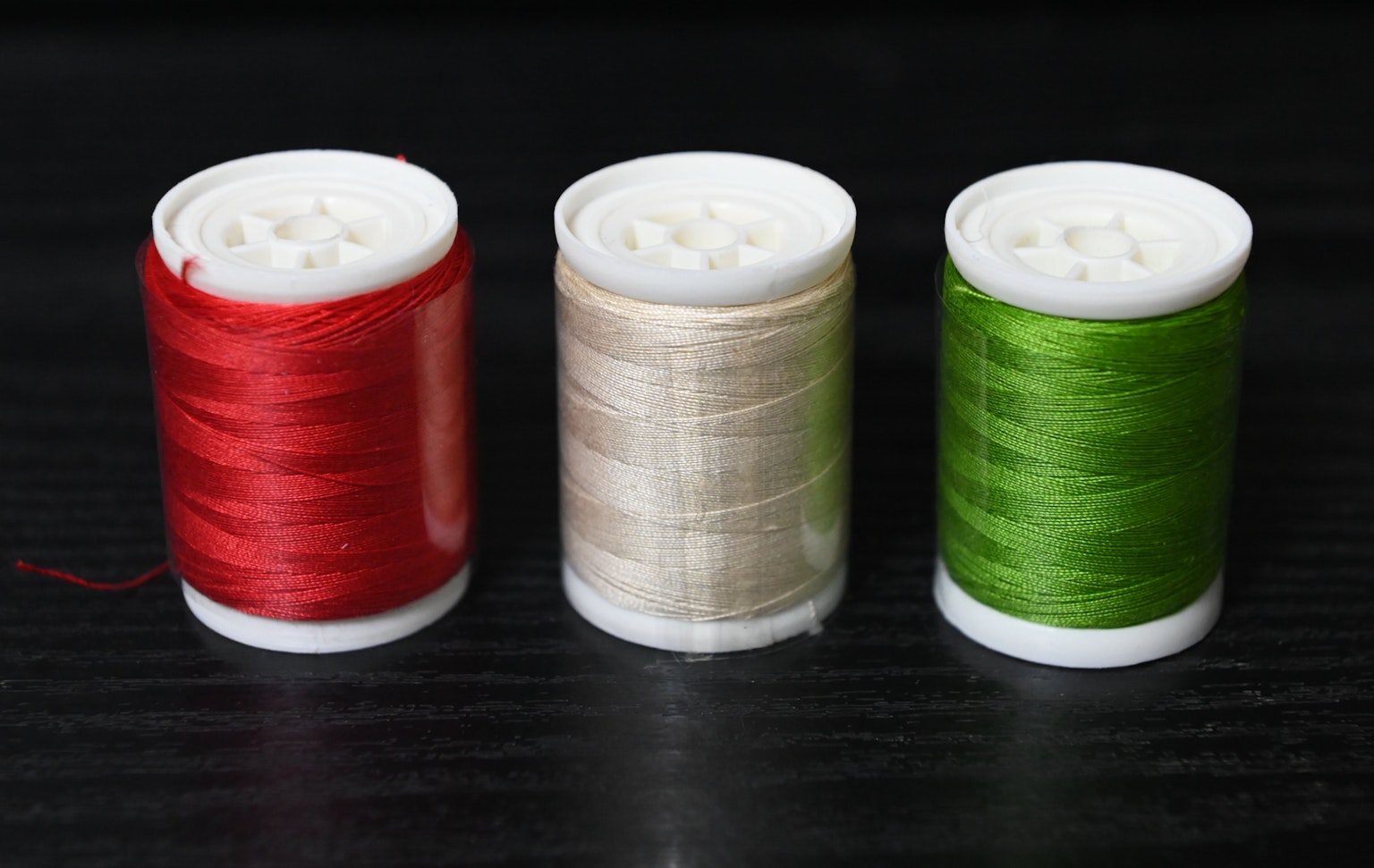 Tre rocchetti di filo nei colori rosso, beige e verde