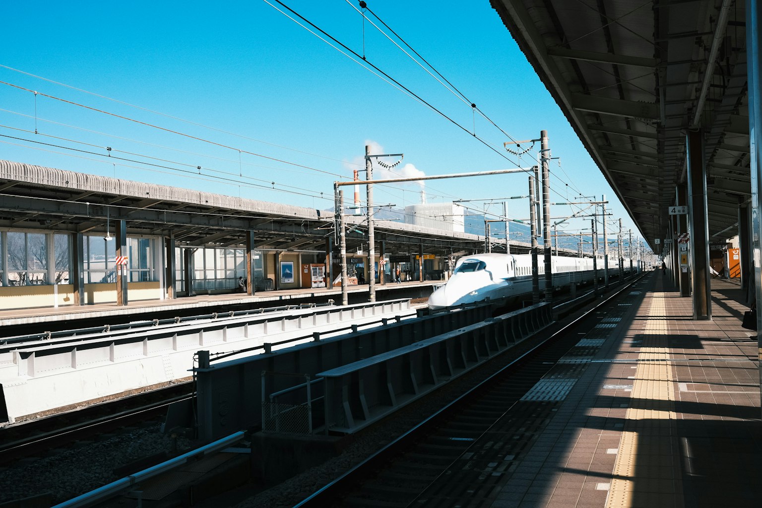 Vue d'une station de Shinkansen avec un train à grande vitesse et un ciel bleu clair