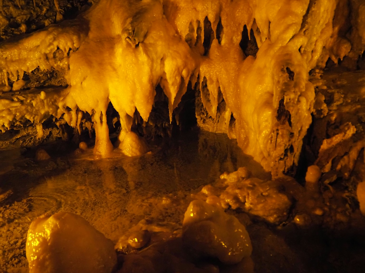 Grotta con stalattiti arancioni e pozzetto d'acqua