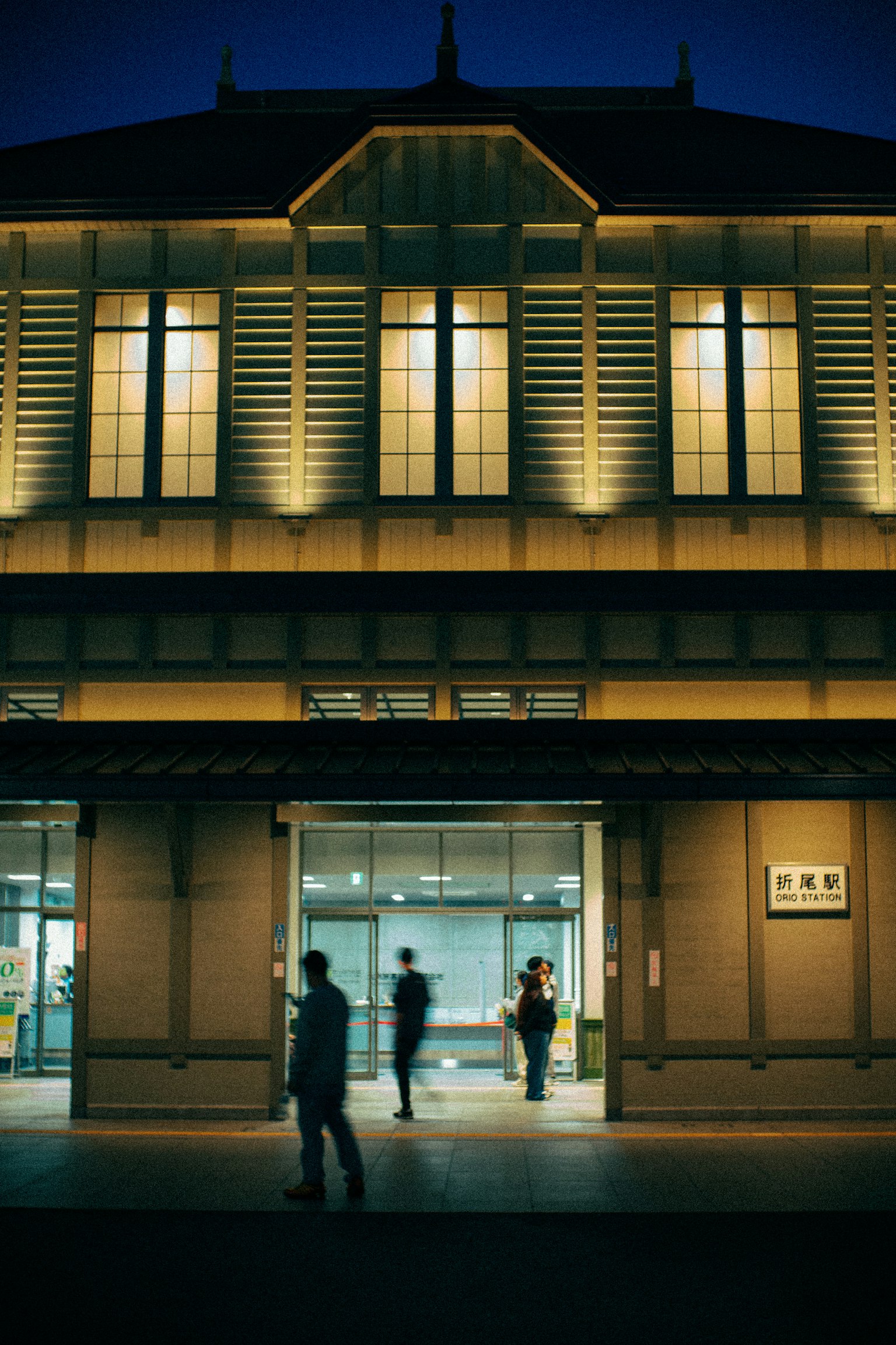 夜の街並みに立つ伝統的な建物の外観と人々のシルエット