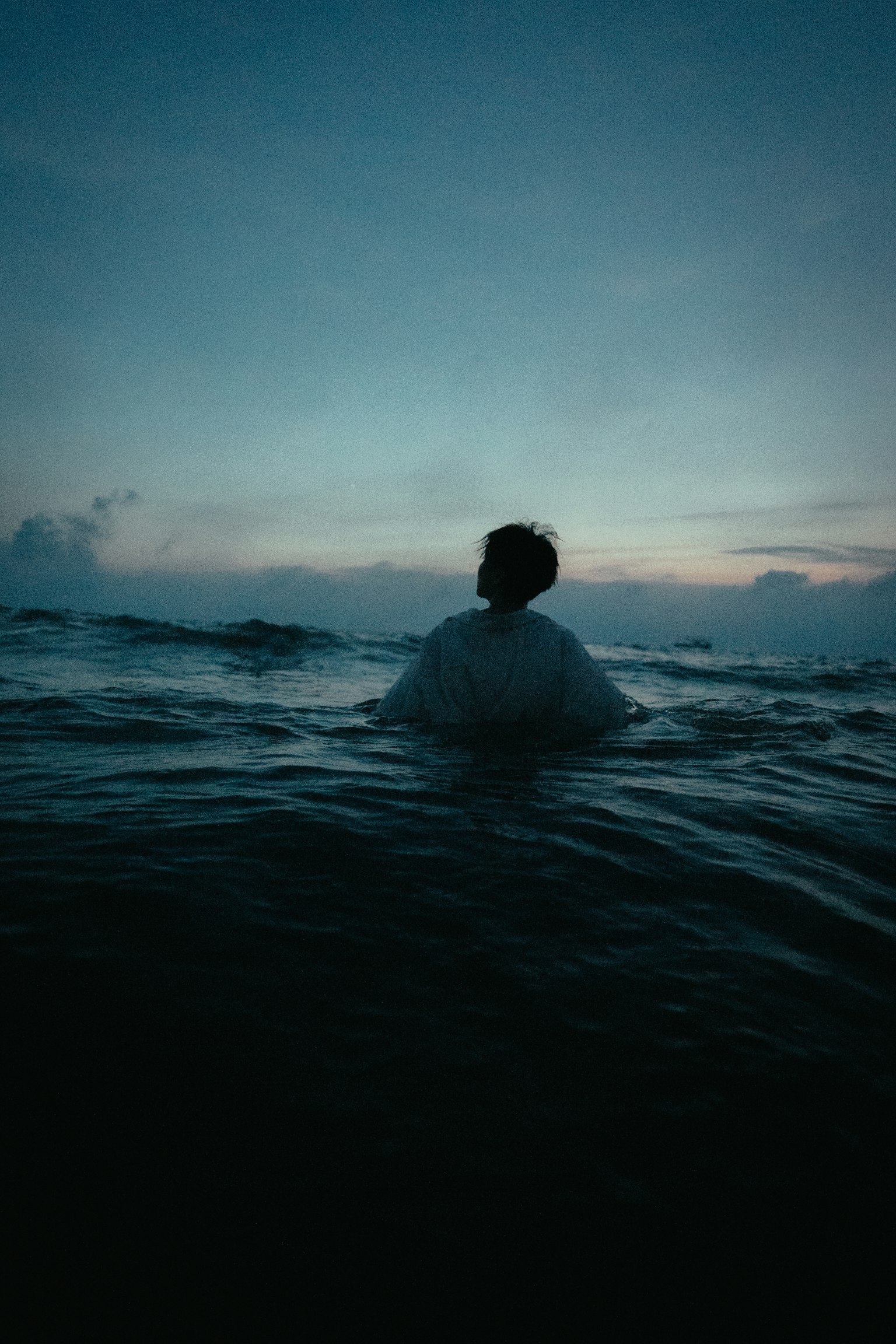 海に浸かる人物のシルエットと青い空の風景