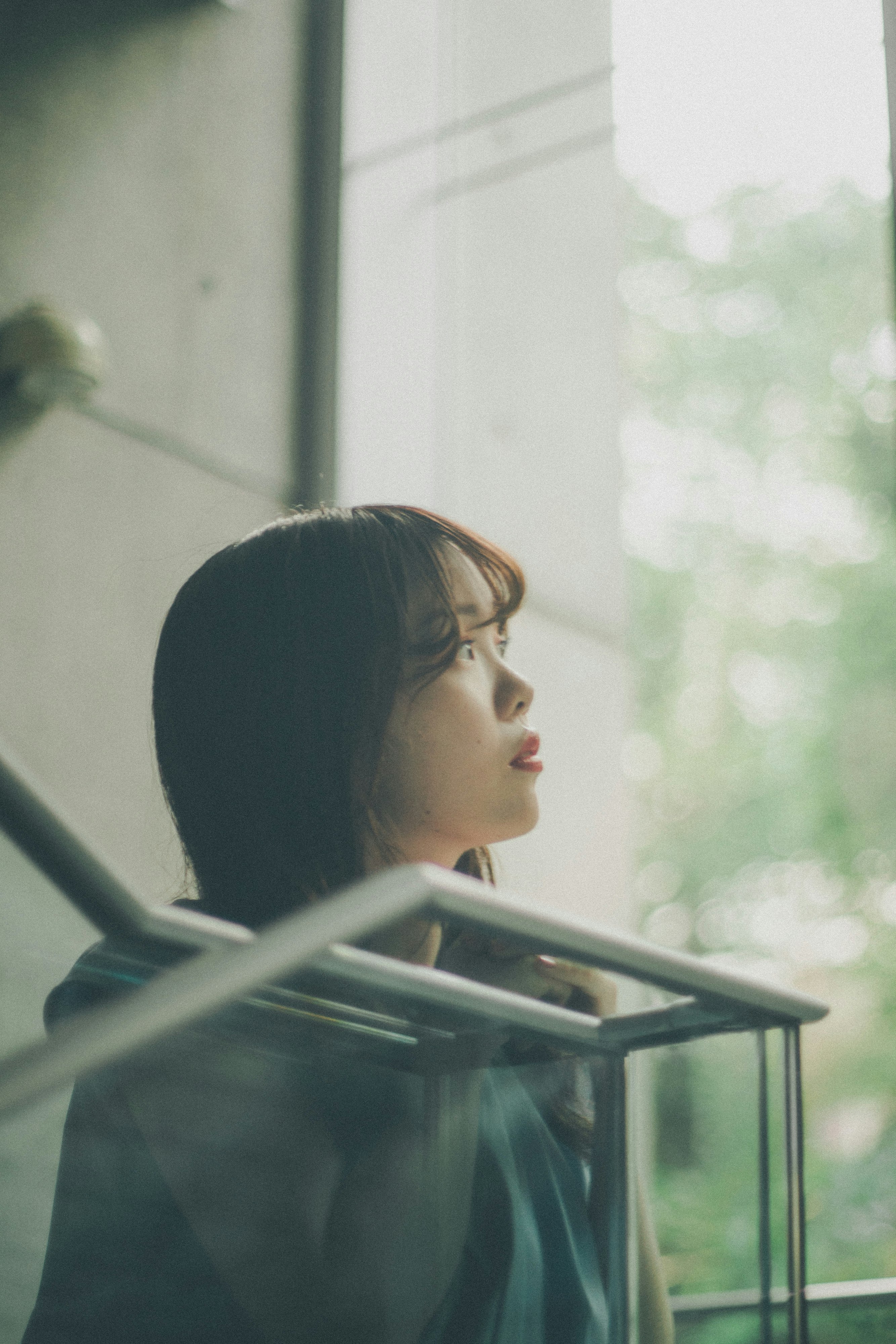 窗邊凝視窗外的女性側臉