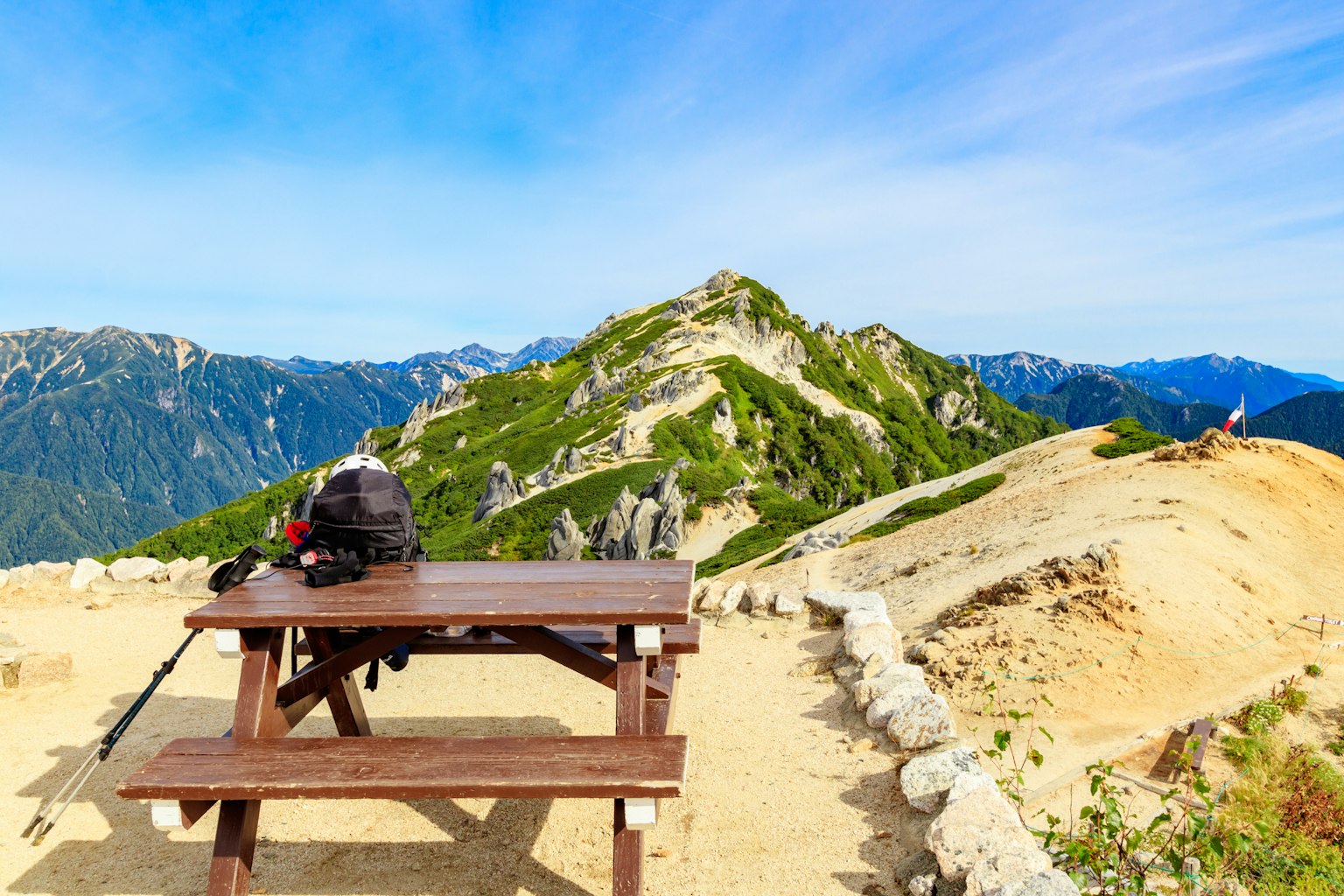 A scenic mountain view with a wooden table and backpack in the foreground